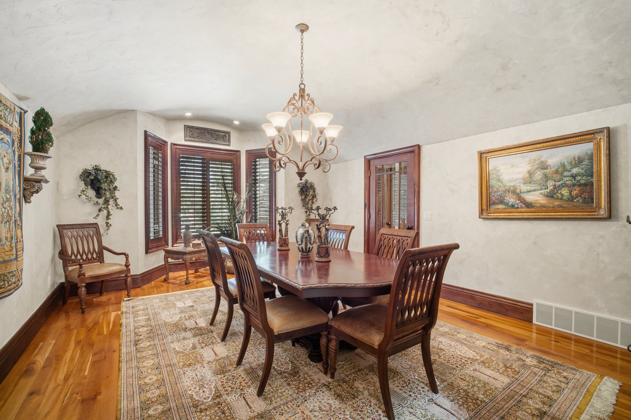 Formal dining area featuring hardwood flooring, a bay window with plantation shutters, a multi-light chandelier, and decorative wall molding