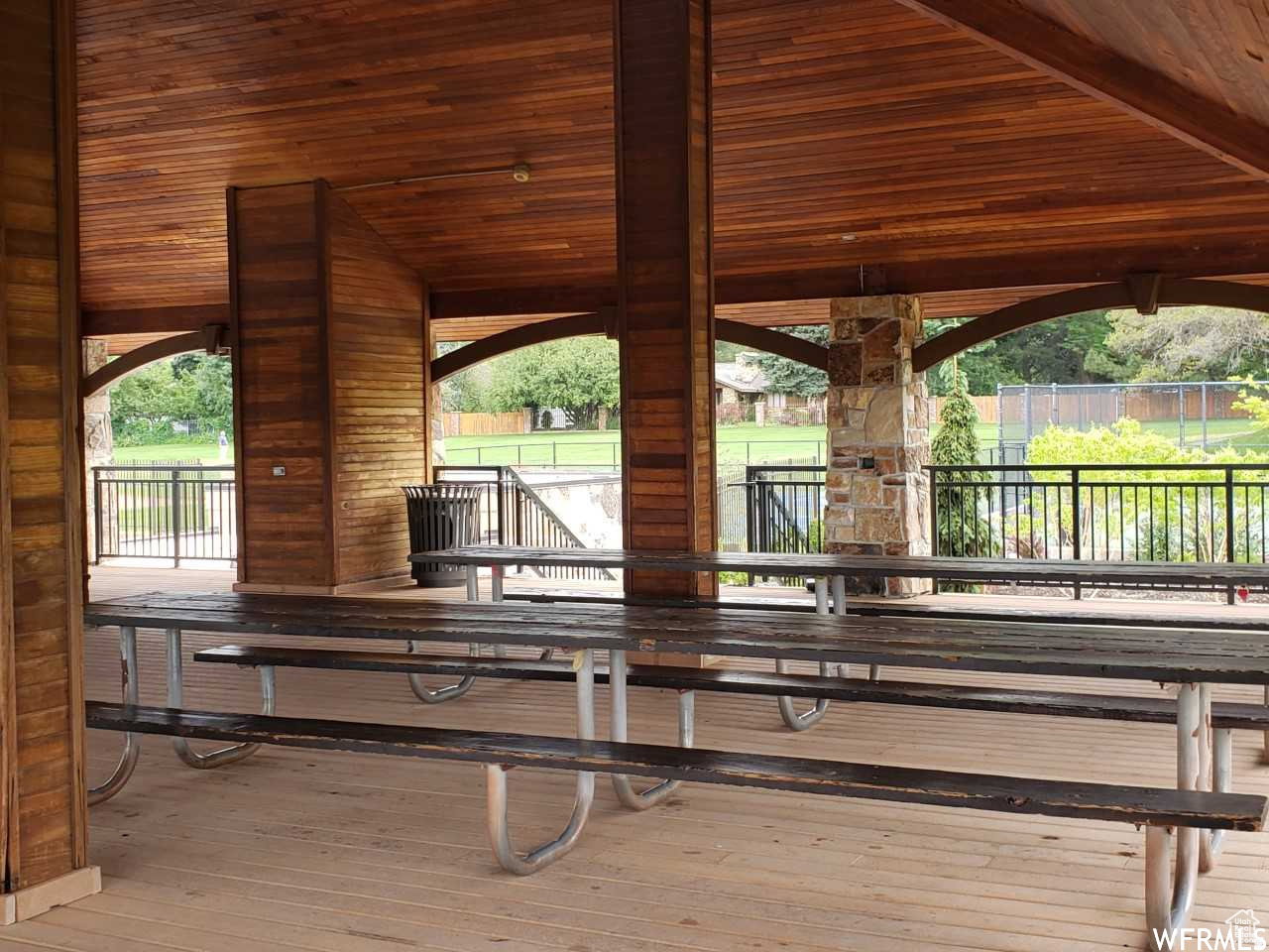 Spacious covered patio area featuring a tongue-and-groove wood ceiling, wood-finish flooring, and exposed wood beams