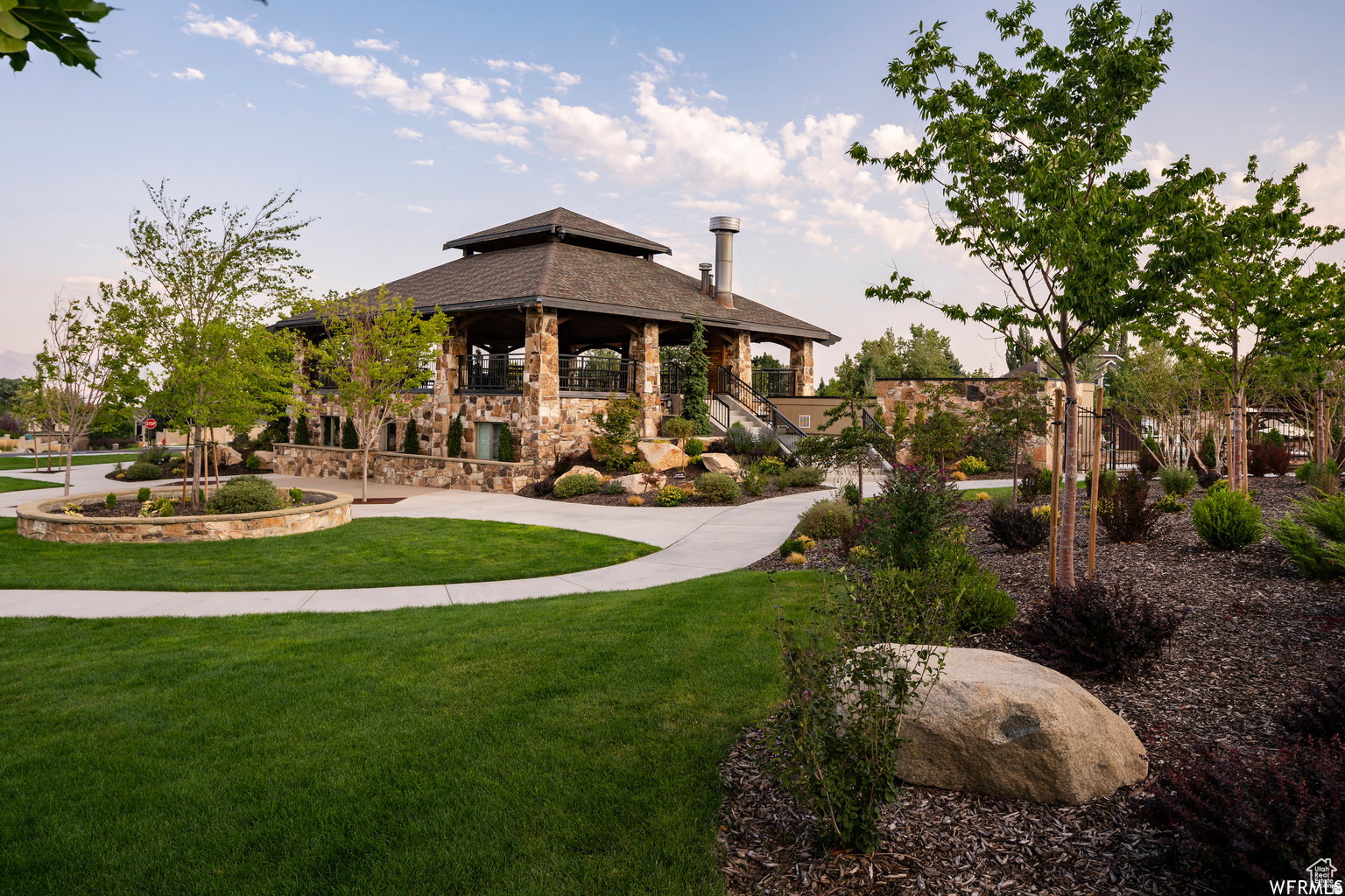 Stone-clad pavilion featuring an expansive patio, multi-level architectural design, and a prominent chimney