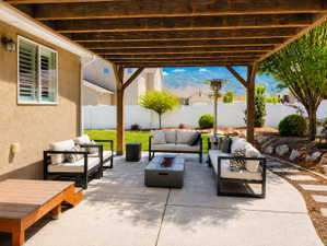 Expansive concrete patio featuring a wood pergola and a built-in fire pit