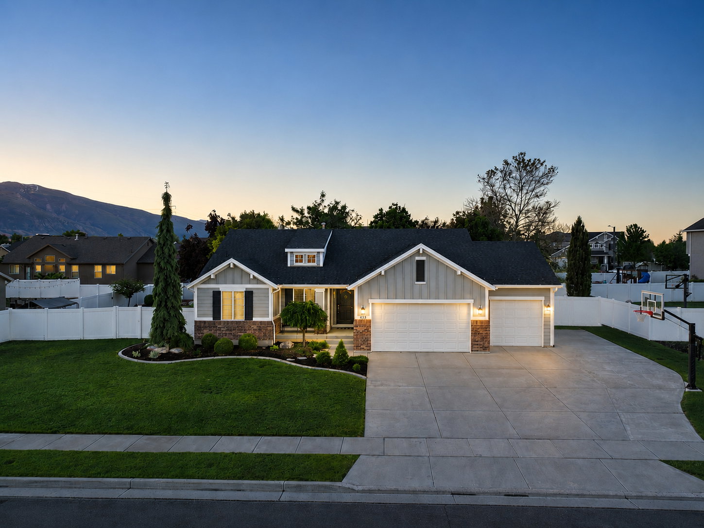 Single-story residence featuring a two-car garage, light gray horizontal siding, dark shingle roofing, and stone accents