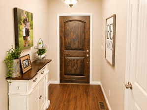 Rich wood-finish flooring complements the dark-stained entry door with an arched top panel