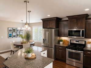 Kitchen and dining area featuring dark wood-finish cabinetry, stainless steel appliances, and wood-finish flooring