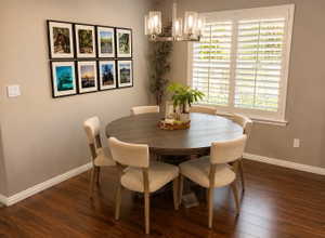 Dining area featuring dark wood-finish flooring, neutral-toned walls, and a window with white plantation shutters