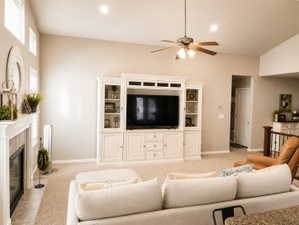 Spacious living area featuring a built-in entertainment center, fireplace with tile surround, vaulted ceiling, recessed lighting, and ceiling fan