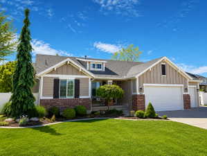 Single-story residence featuring a two-car garage with white door, tan siding, and brick accents