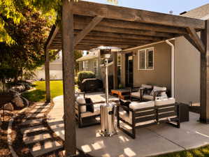 Expansive concrete patio featuring a wood pergola structure, a stepped garden path, and a manicured lawn