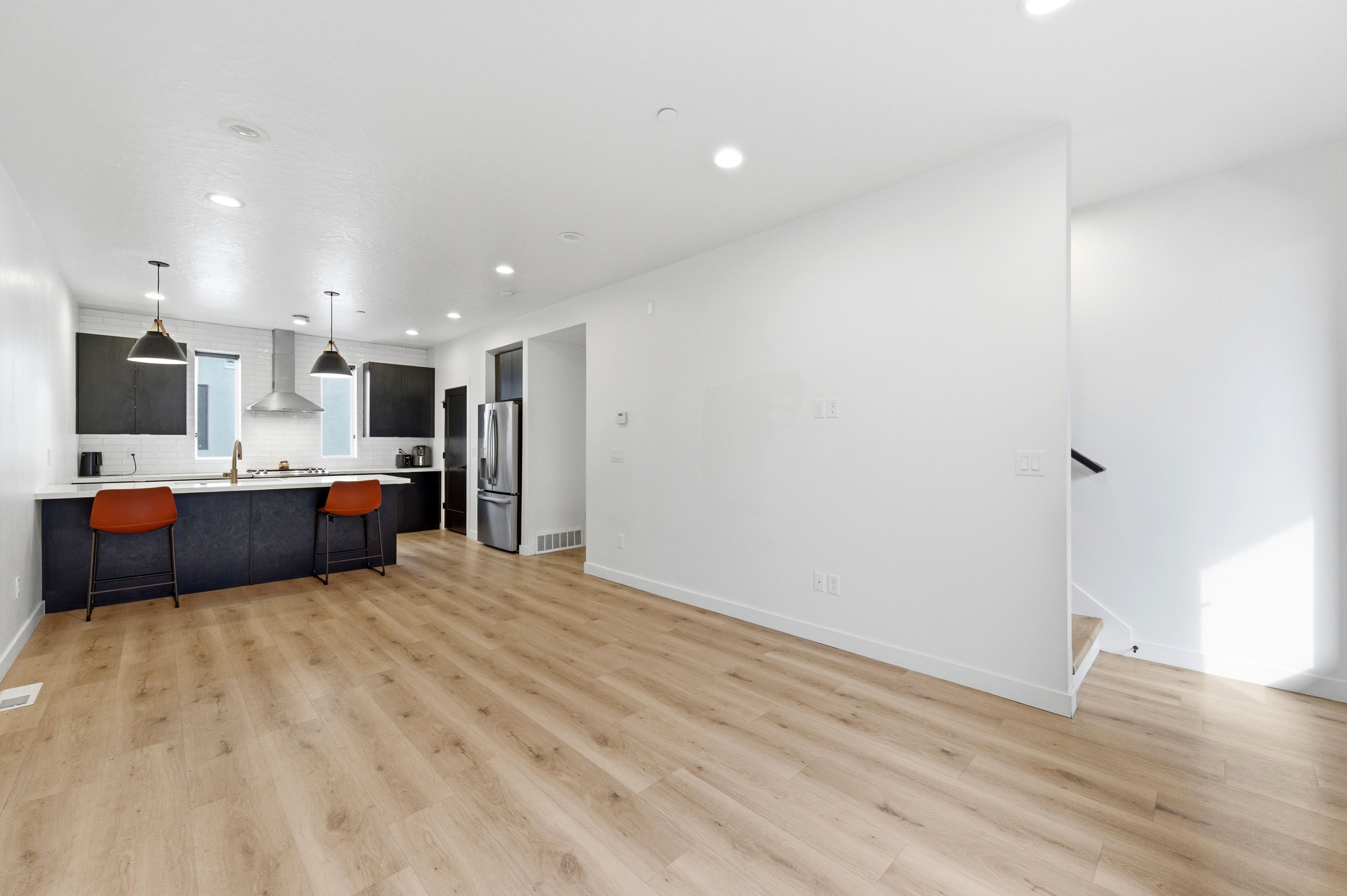 Open-concept living space with light wood-finish flooring, recessed lighting, and a contemporary kitchen