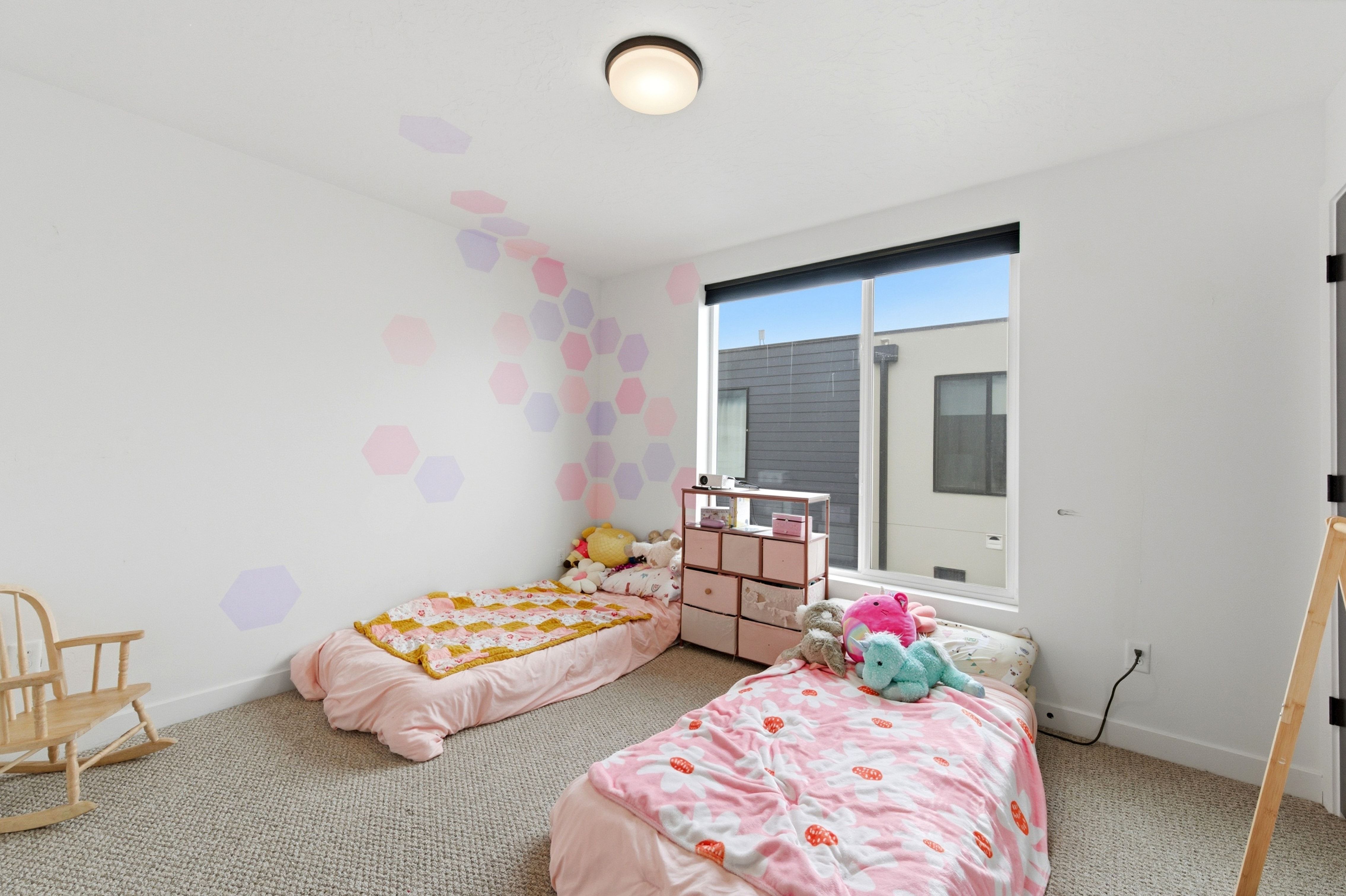 Spacious room featuring a large window, neutral carpeting, white walls, and a flush-mount ceiling light