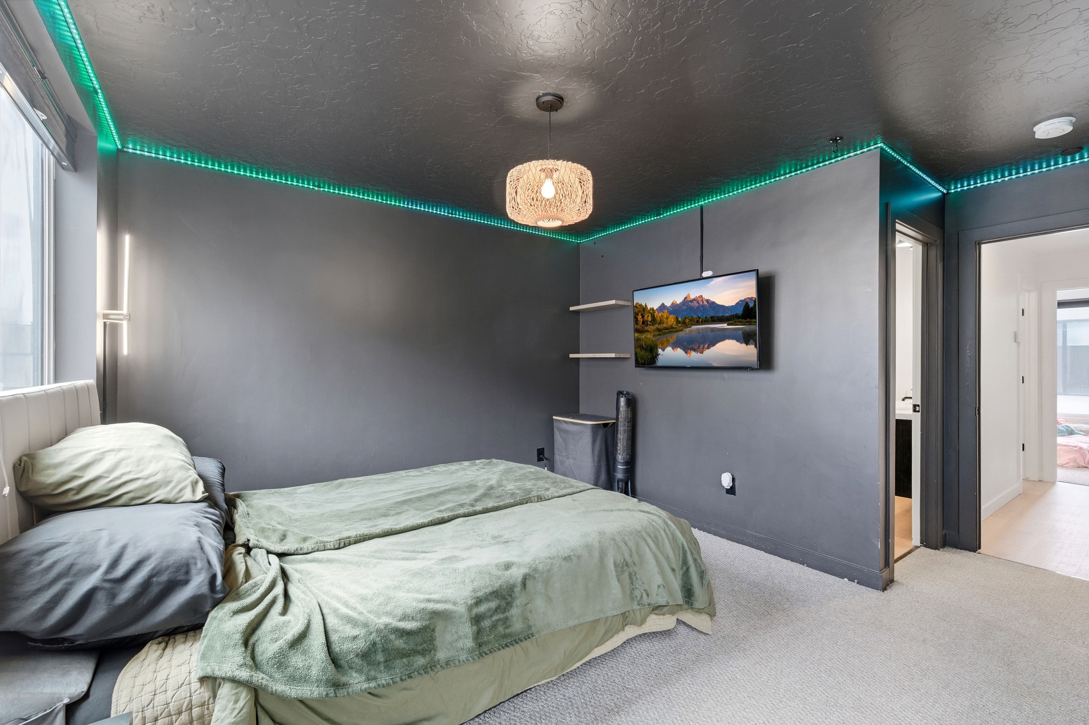 Interior room featuring dark gray walls and ceiling, carpet flooring, a wall-mounted television, and recessed ceiling lighting