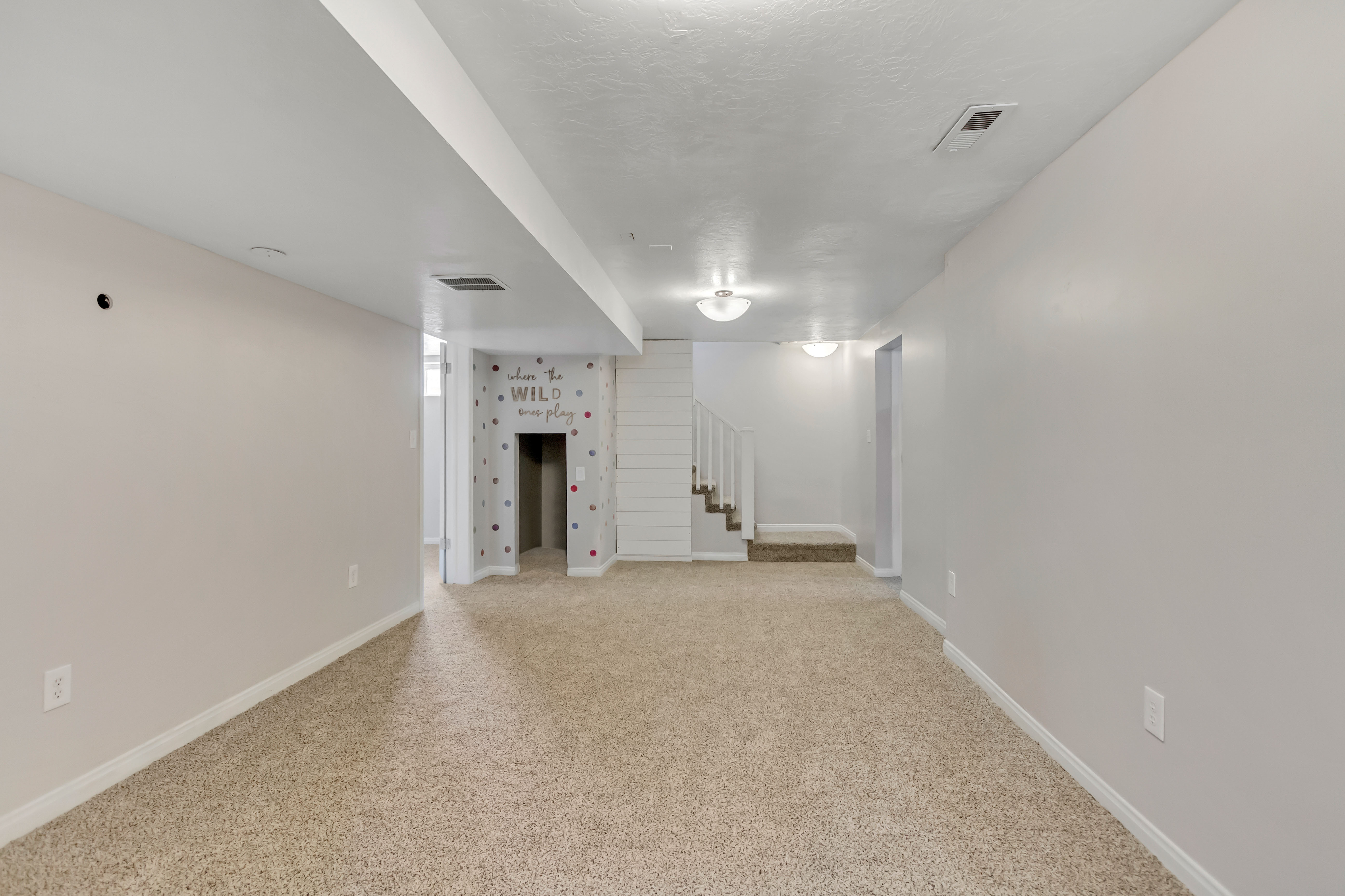 Spacious interior room featuring light beige carpeting and neutral wall paint