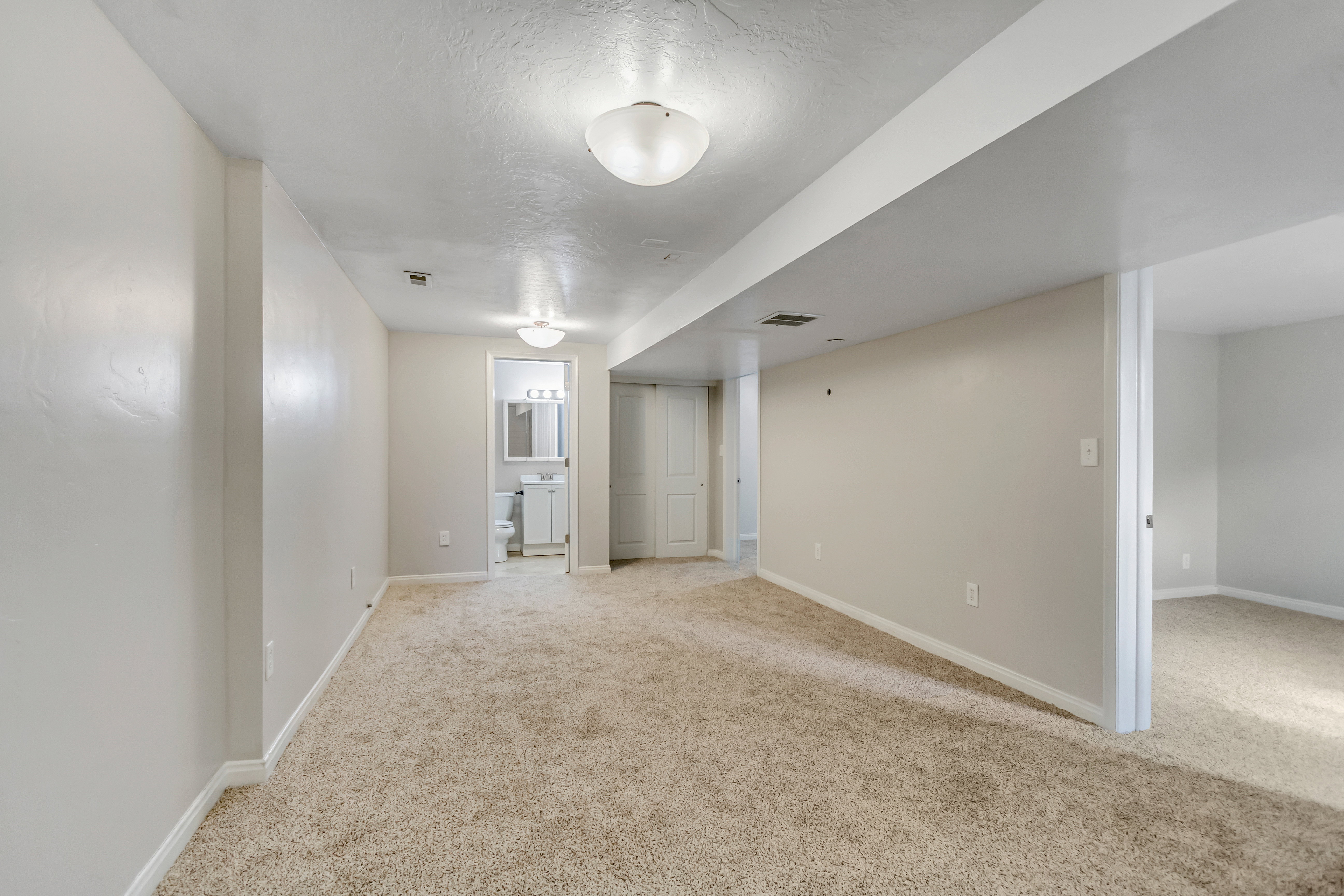 Carpeted open-concept room with neutral wall tones and recessed lighting