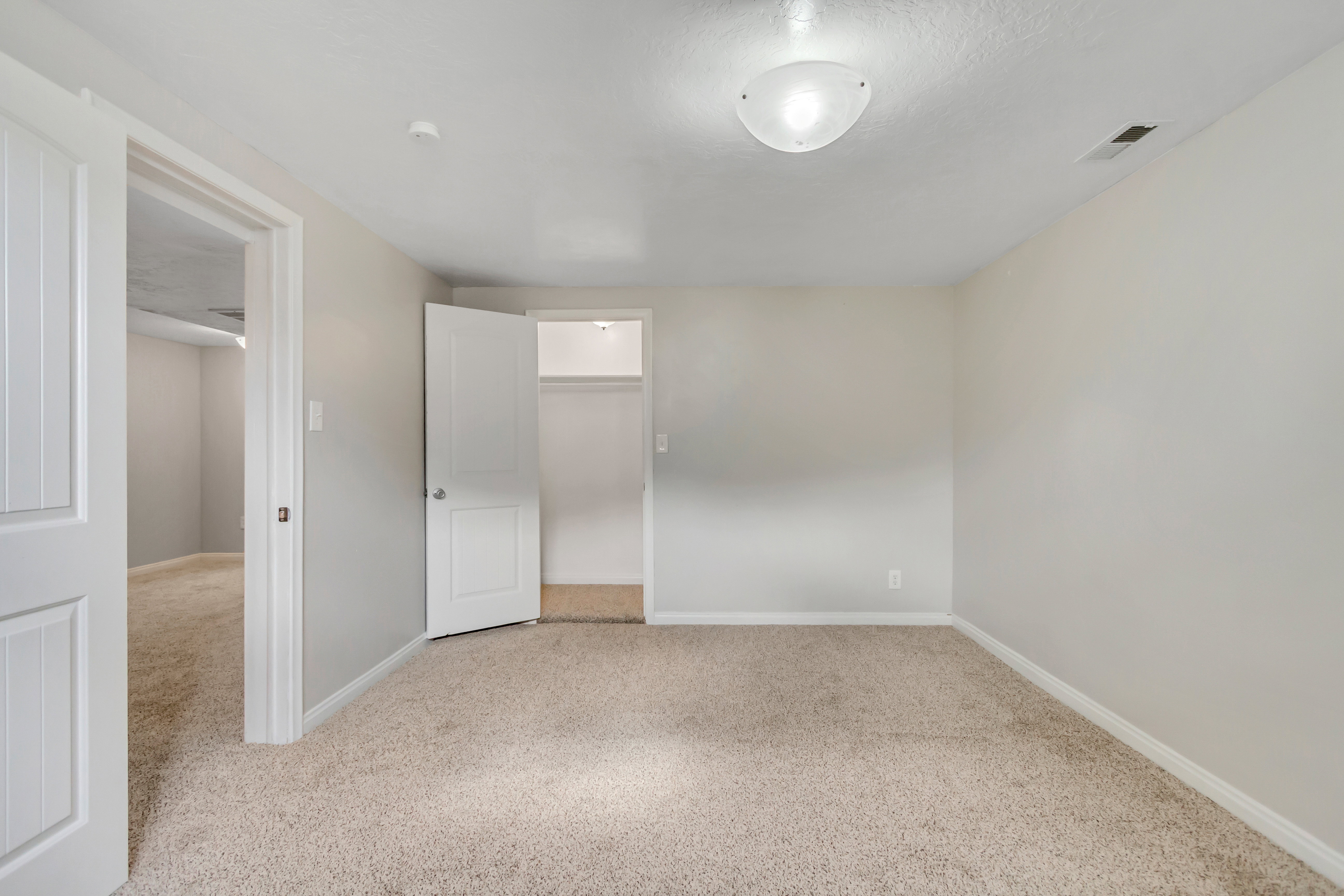 Carpeted interior space featuring neutral wall tones, white trim, a flush mount ceiling light fixture, and a single closet