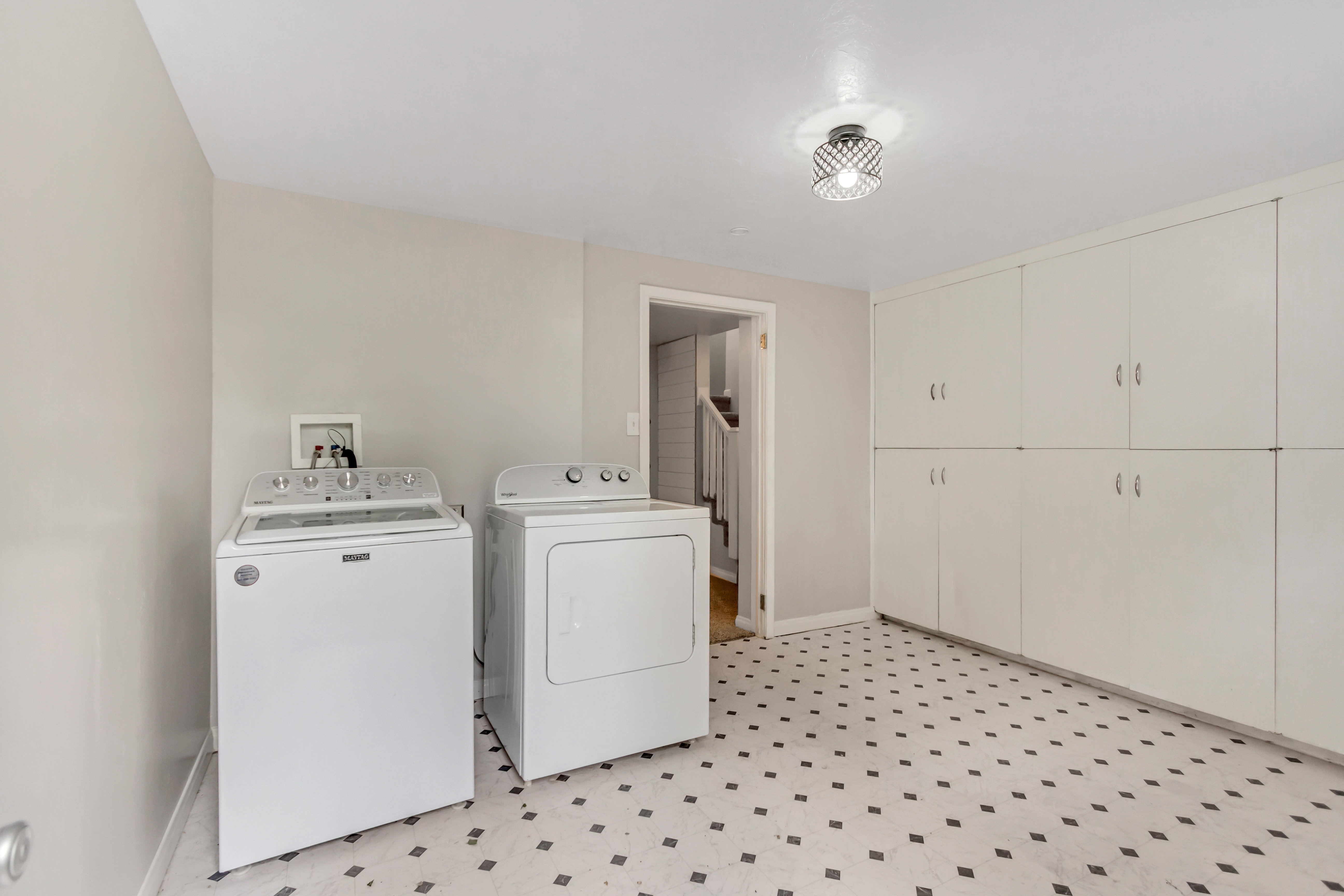 Dedicated utility room featuring patterned floor tile, built-in cabinetry, and overhead lighting
