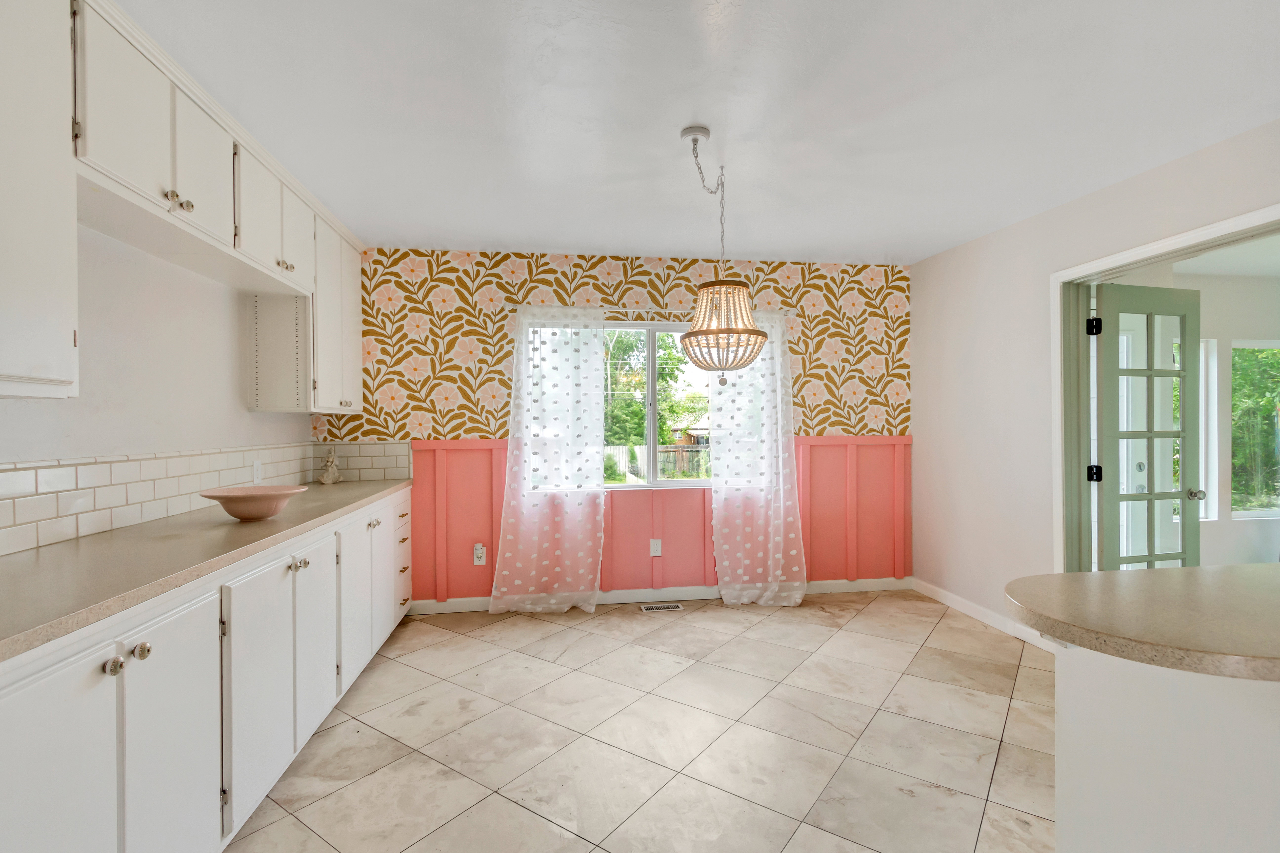 Bright kitchen and dining area featuring white cabinetry, subway tile backsplash, and a breakfast bar