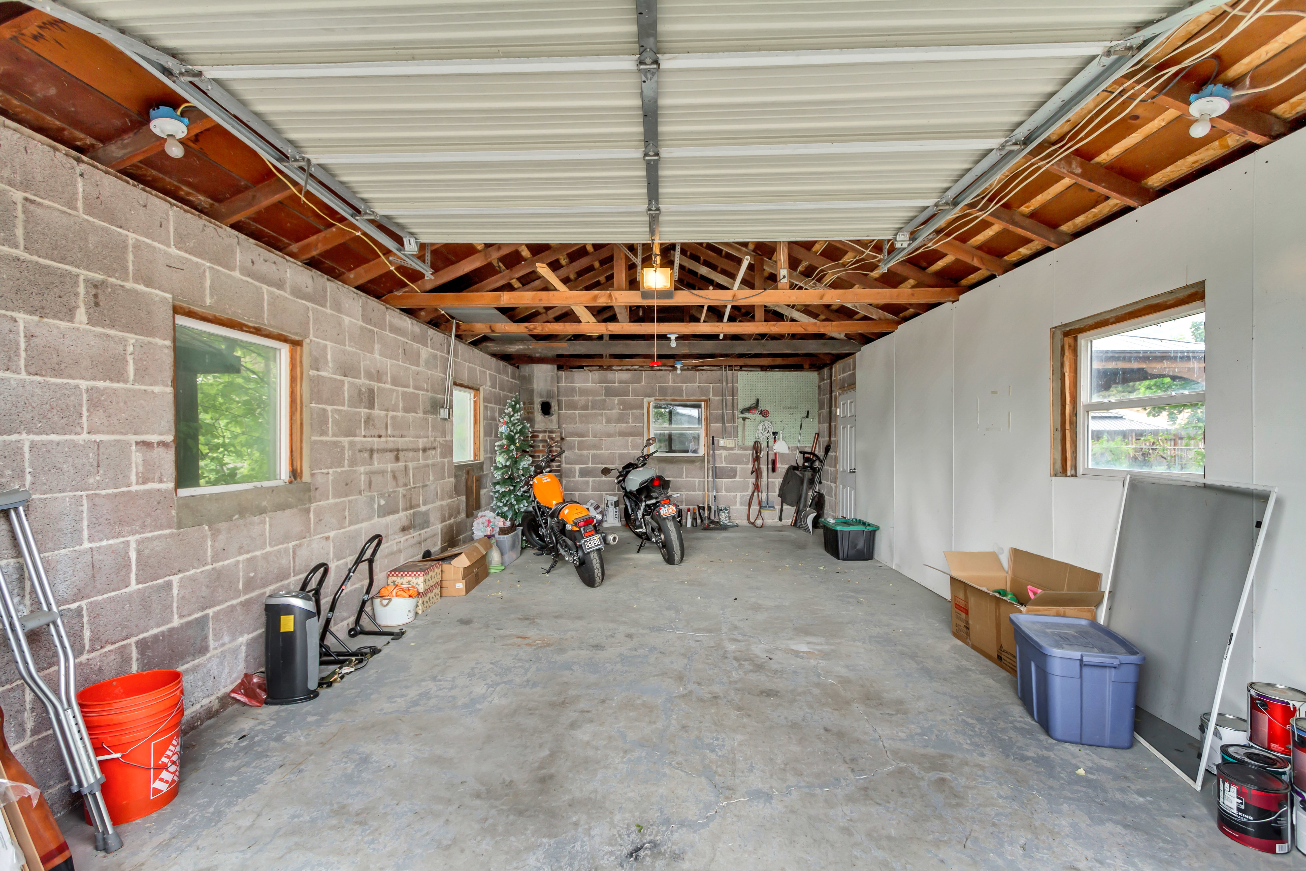 Interior garage space featuring a concrete floor, exposed wood ceiling beams, and a metal ceiling