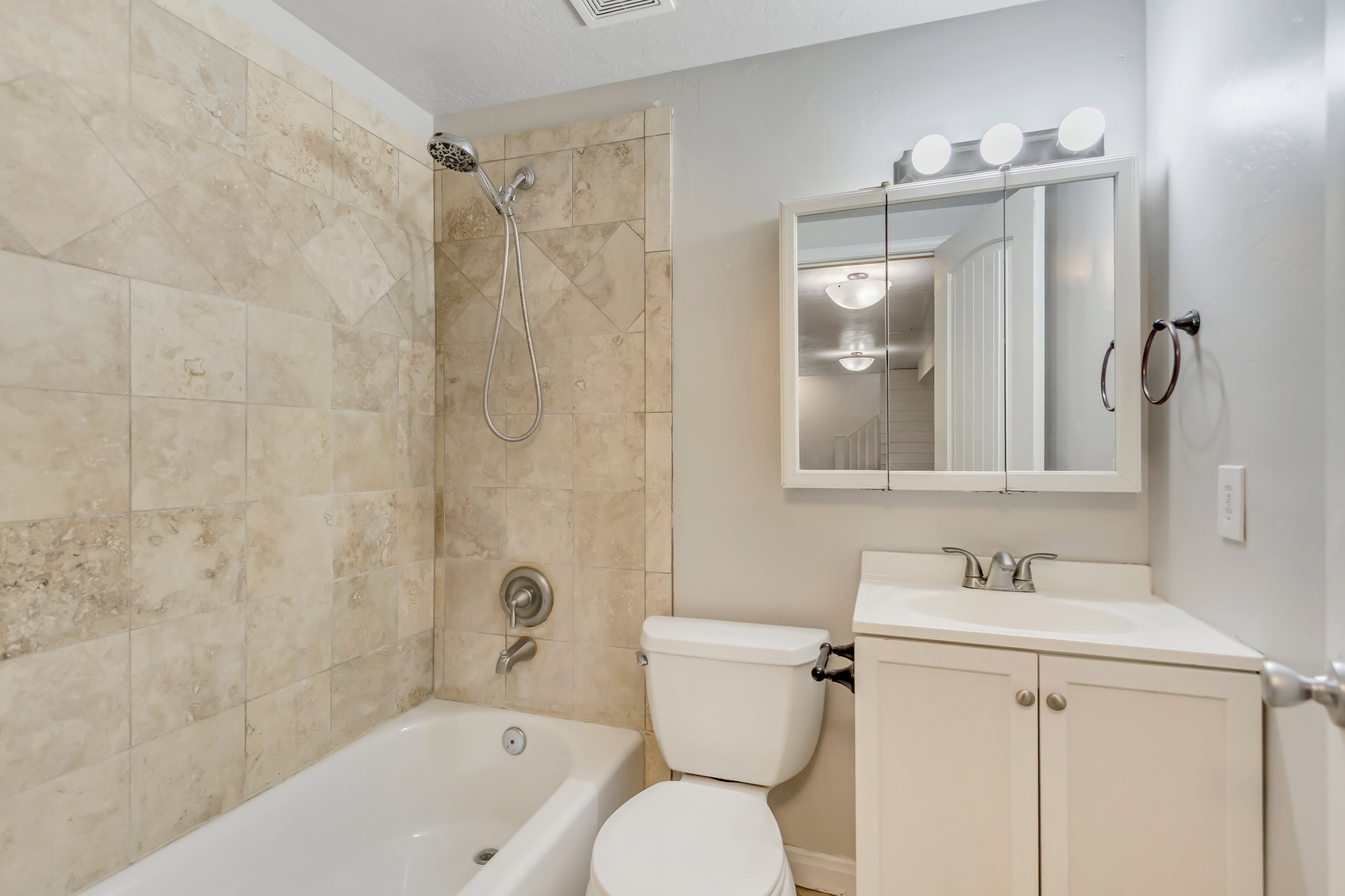 Bathroom featuring a full tub and shower with stone-look tile surround
