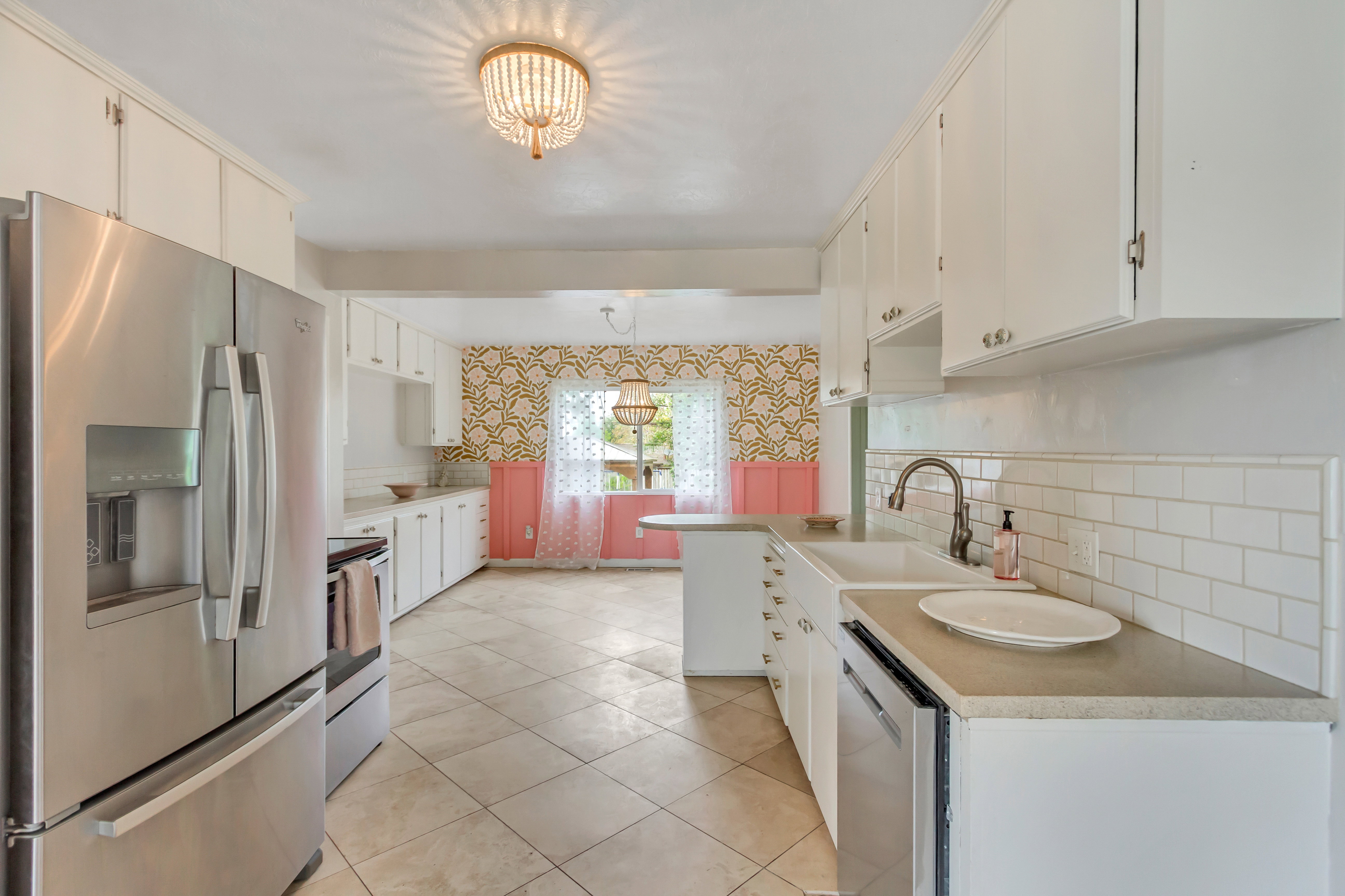 Kitchen featuring light tile flooring, white cabinetry, stainless steel appliances, white subway tile backsplash, and a double basin sink