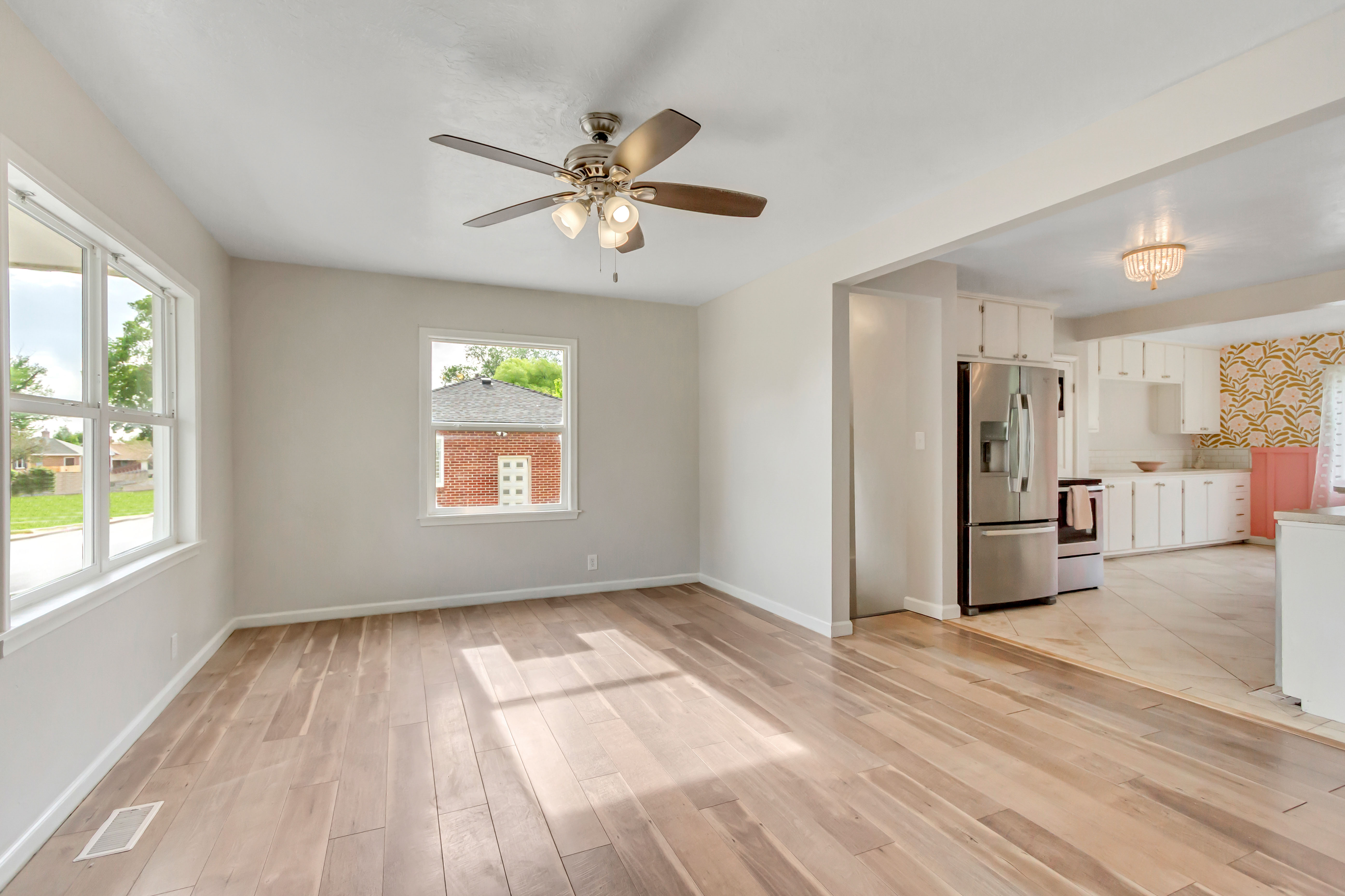 Spacious room featuring wood-finish flooring, light neutral wall paint, and multiple windows for natural light