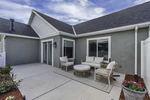 Expansive concrete patio with stucco exterior, dual glass panel doors, and large sliding windows
