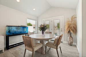 Dining area featuring wood-look tile flooring and a vaulted ceiling