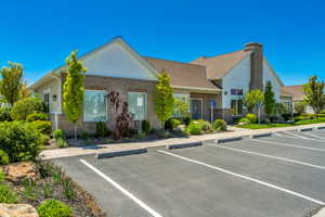 Building exterior featuring a brick and siding facade, a shingle roof, mature landscaping, and an asphalt parking lot