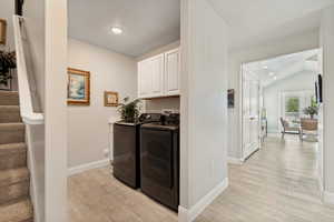 Laundry area featuring white cabinetry, a built-in sink, and wood-finish flooring