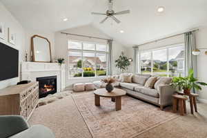 Living room featuring a vaulted ceiling with a ceiling fan, recessed lighting, and large windows