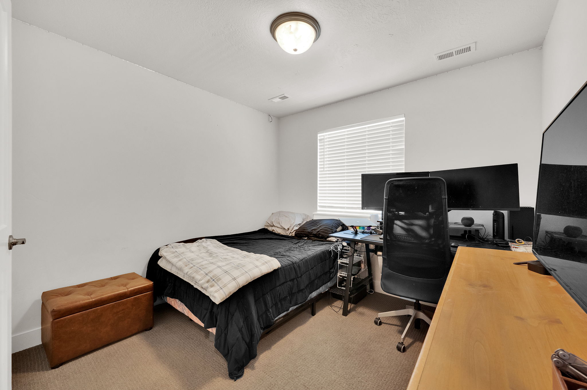 Carpeted room featuring a single window with blinds, white walls, and a ceiling-mounted light fixture