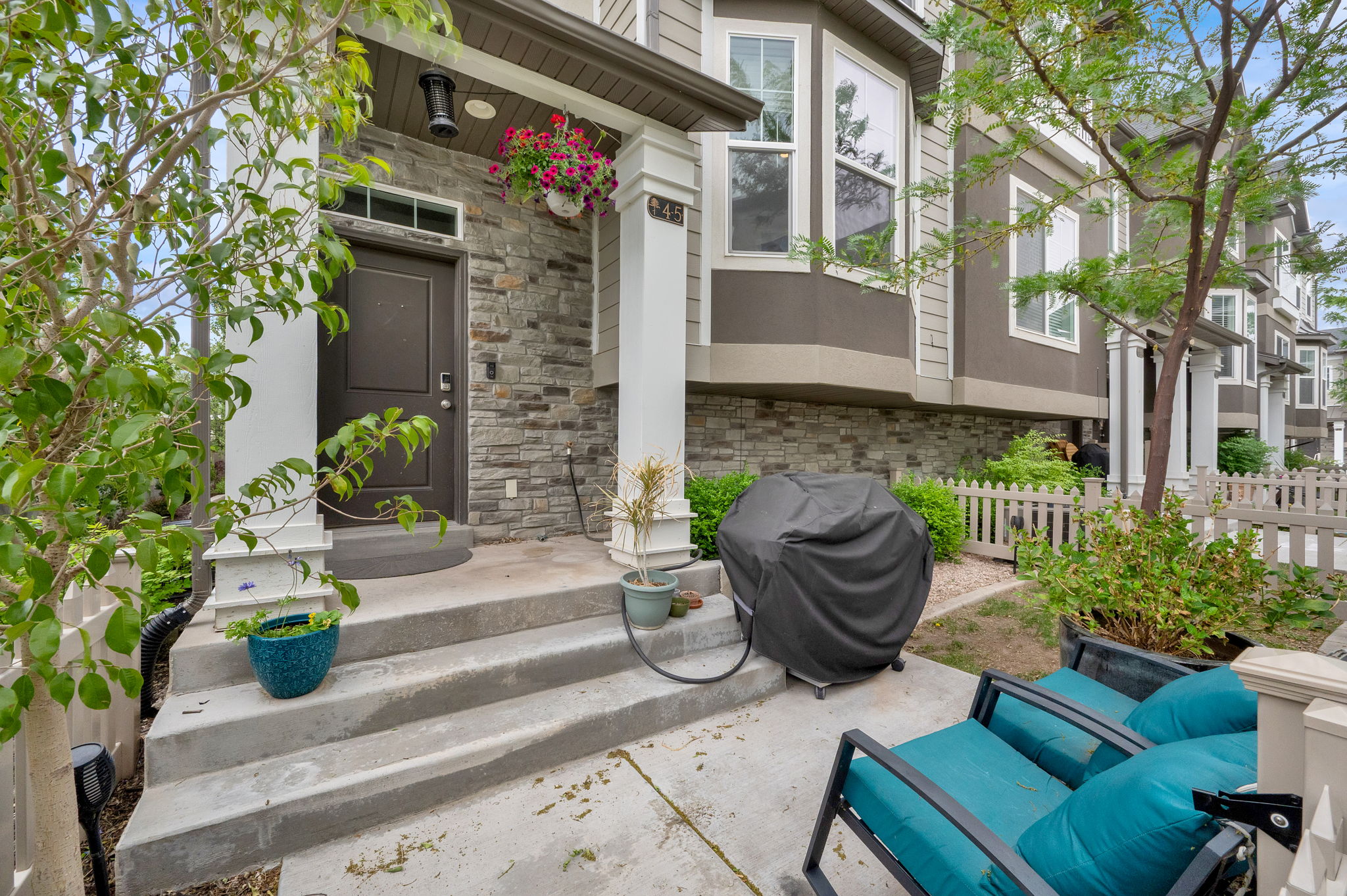 Stone veneer exterior with a prominent front door, concrete steps, and white architectural columns