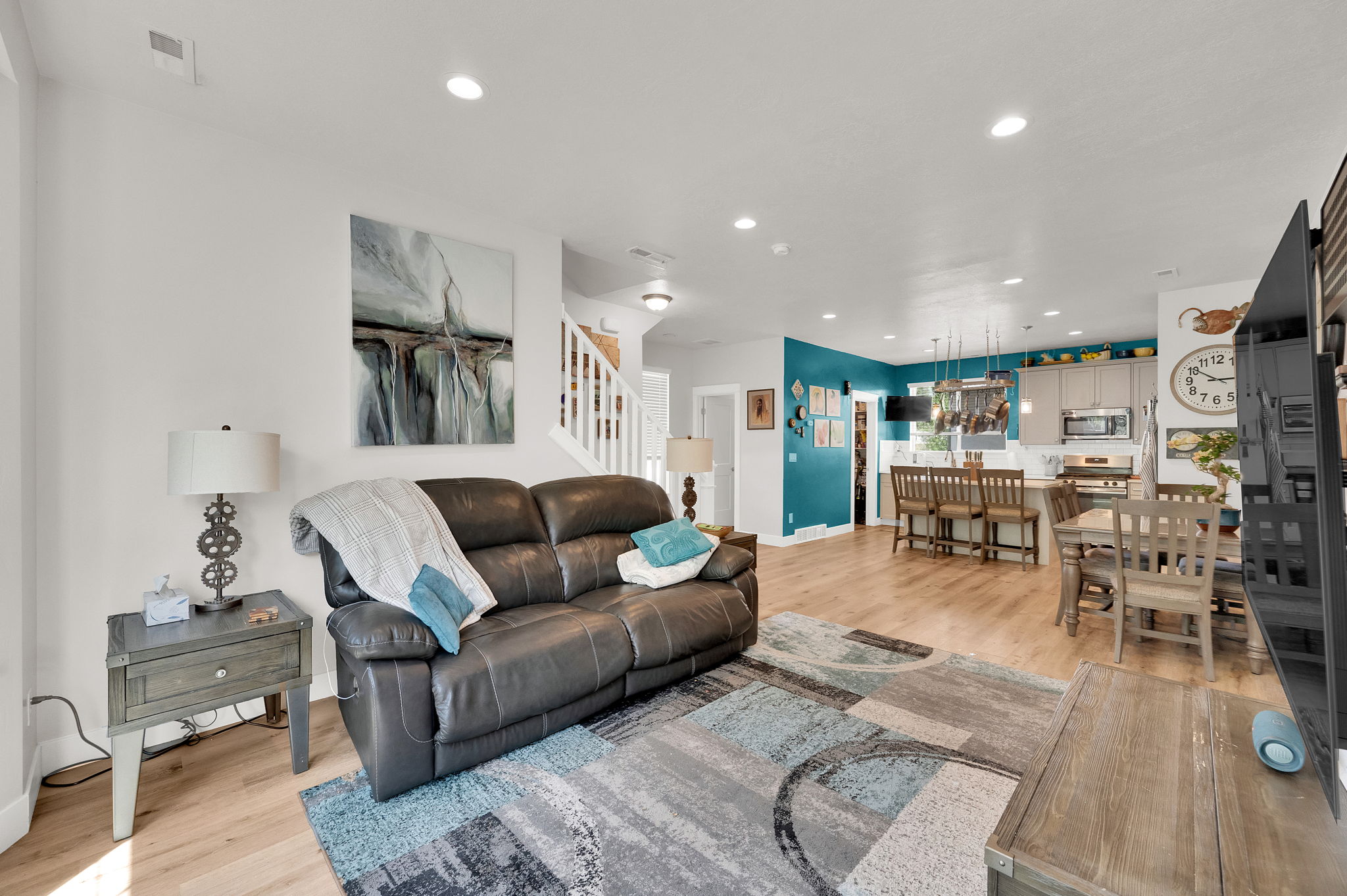 Open-concept living space featuring wood-finish flooring, recessed lighting, and a prominent accent wall
