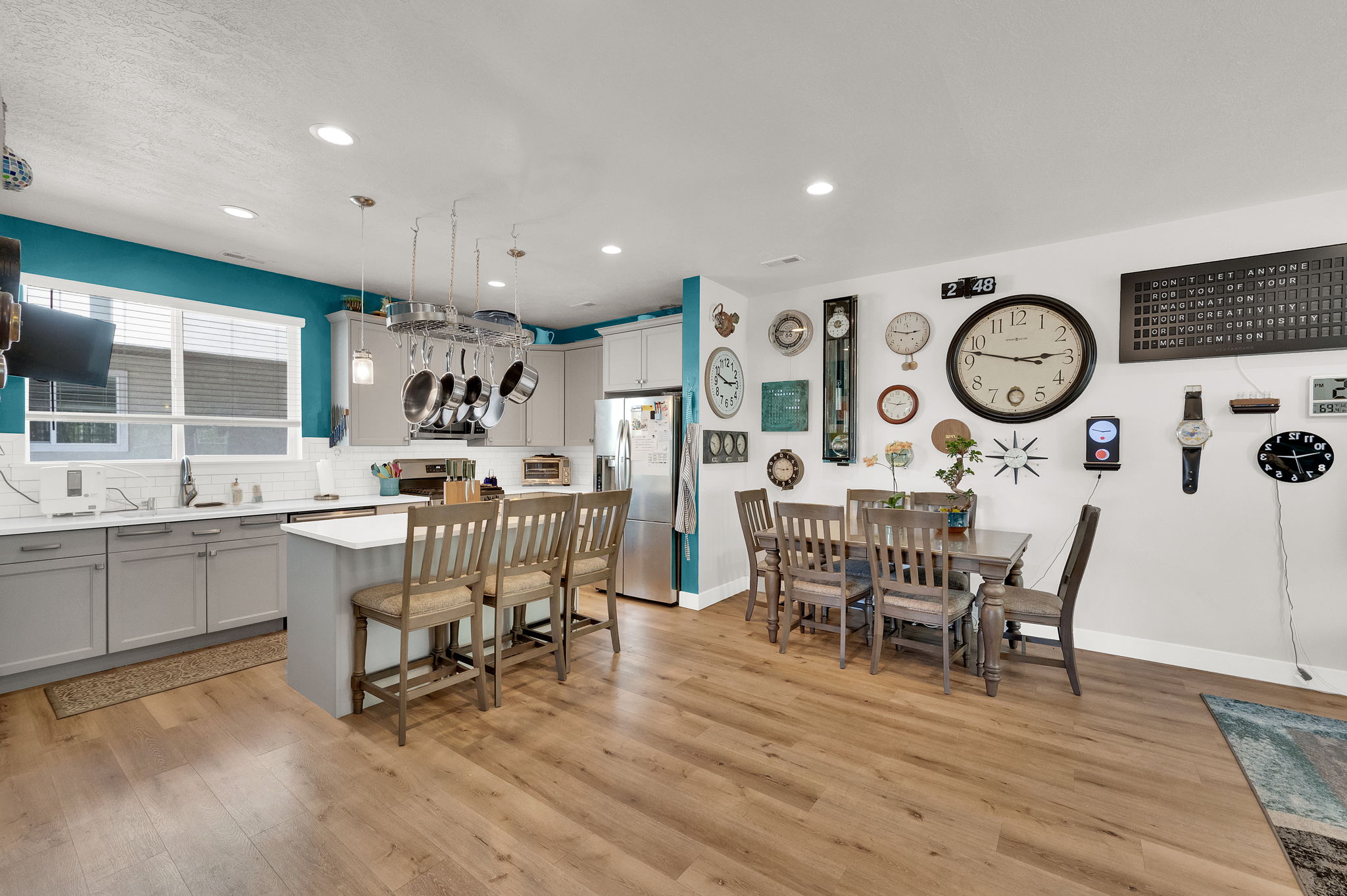 Open-concept kitchen and dining area featuring wood-finish flooring, recessed lighting, and a pot rack