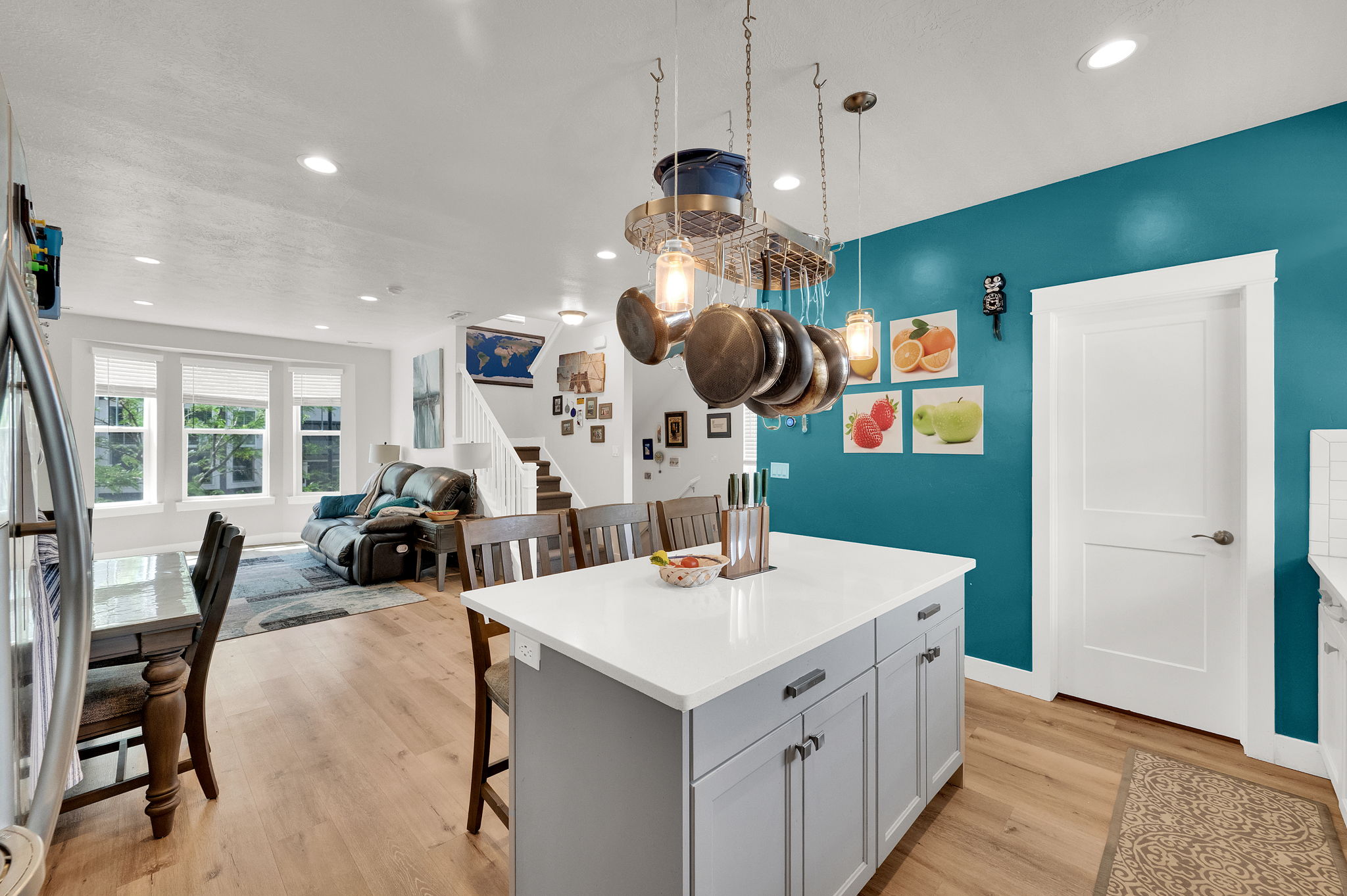 Kitchen island with light gray cabinetry, a white countertop, and a pot rack light fixture