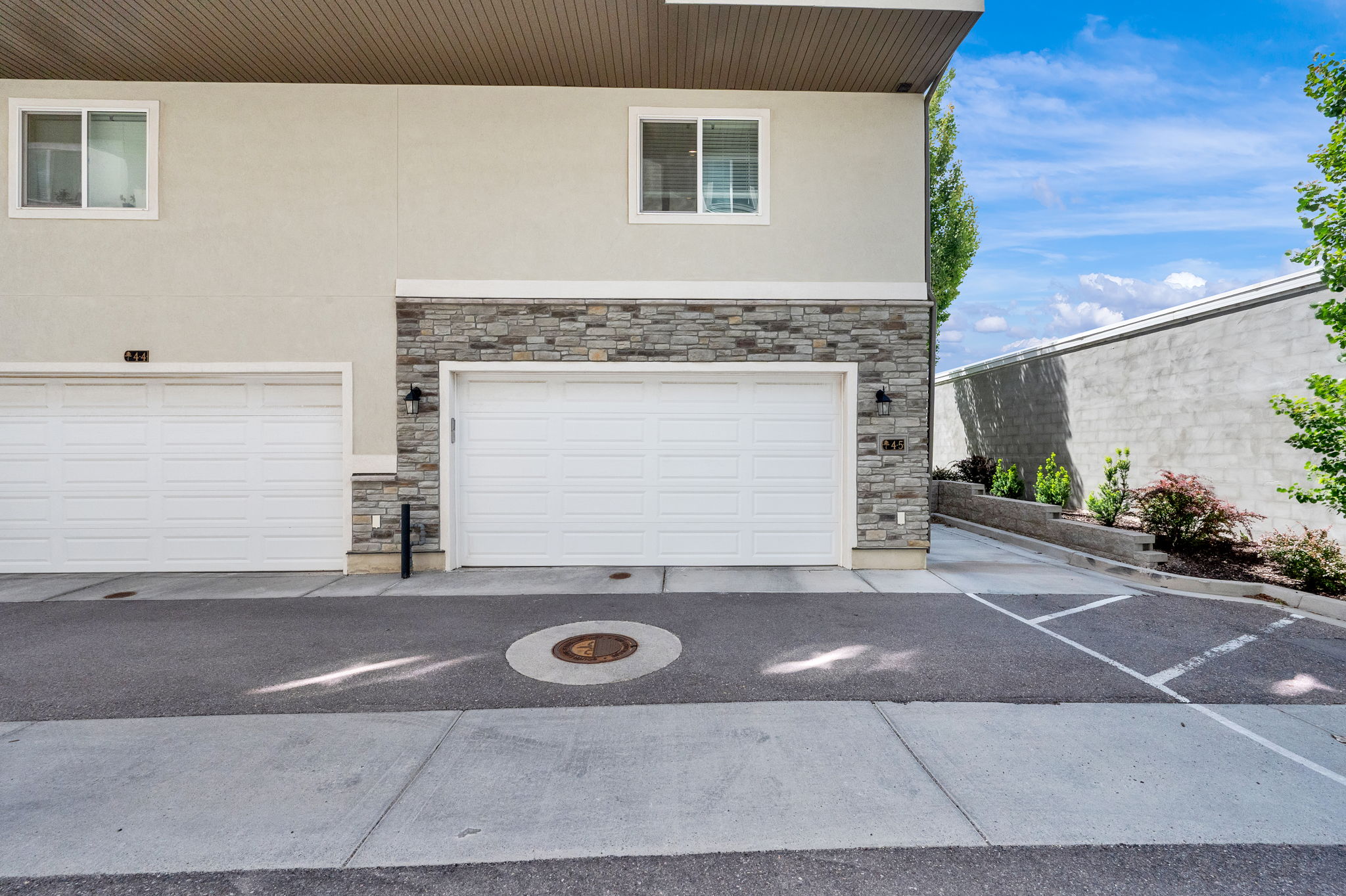 Multi-unit facade featuring dual garage doors, stone veneer accents, and stucco siding