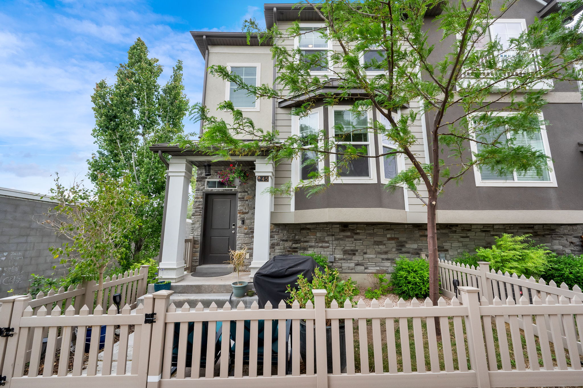 Multi-story residence featuring a stone veneer foundation, bay windows, and a covered entry porch with white columns