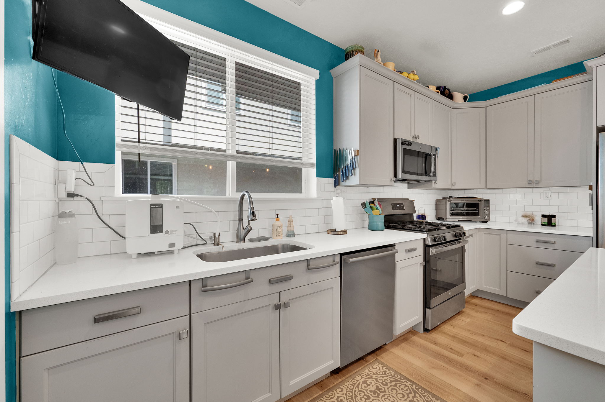 Modern kitchen featuring light gray cabinetry with brushed nickel hardware, white countertops, and a white subway tile backsplash