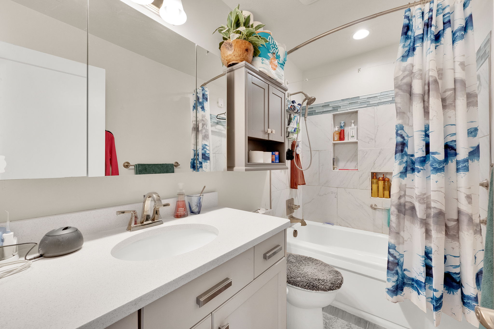 Full bathroom featuring a white vanity with a single basin sink, medicine cabinet mirror, and a tiled tub/shower combination