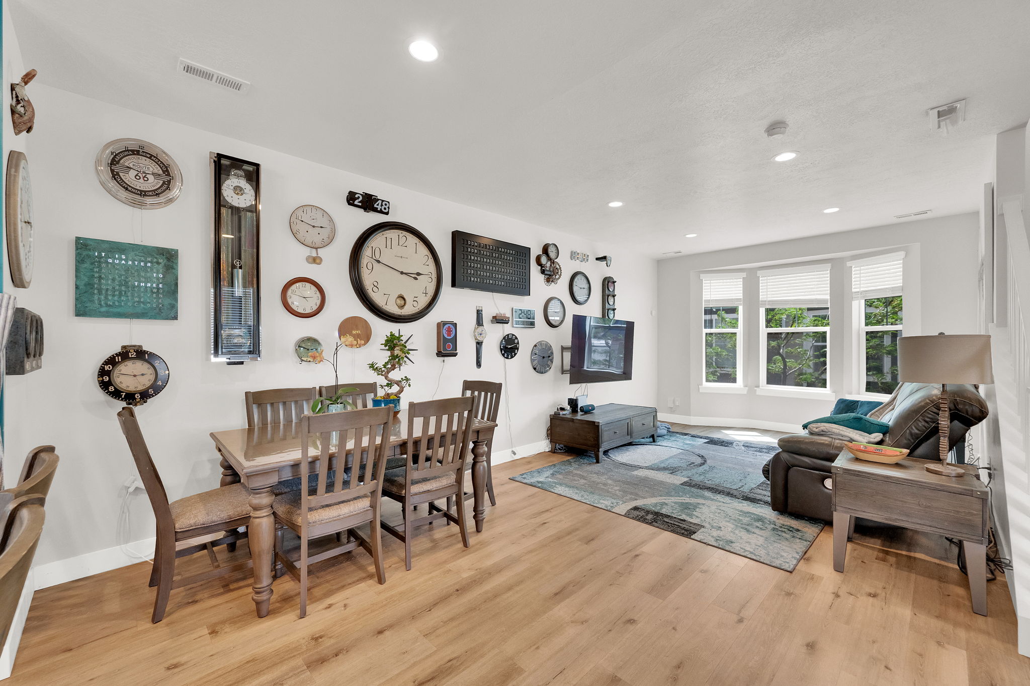 Open-concept living area featuring wood-finish flooring, recessed lighting, and a bay window with multiple panes