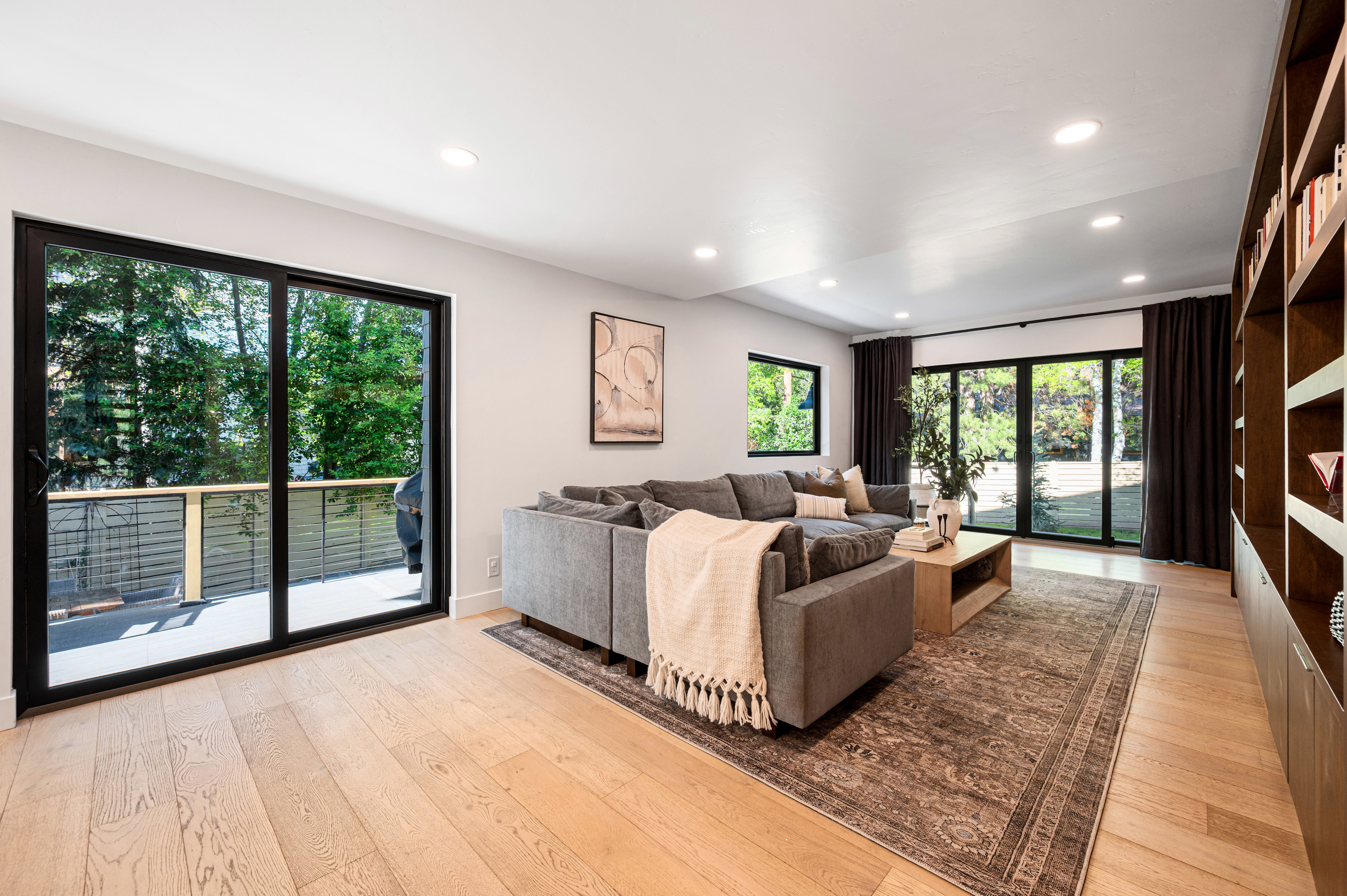 Spacious living area featuring light wood-finish flooring, recessed lighting, and built-in shelving with integrated cabinetry