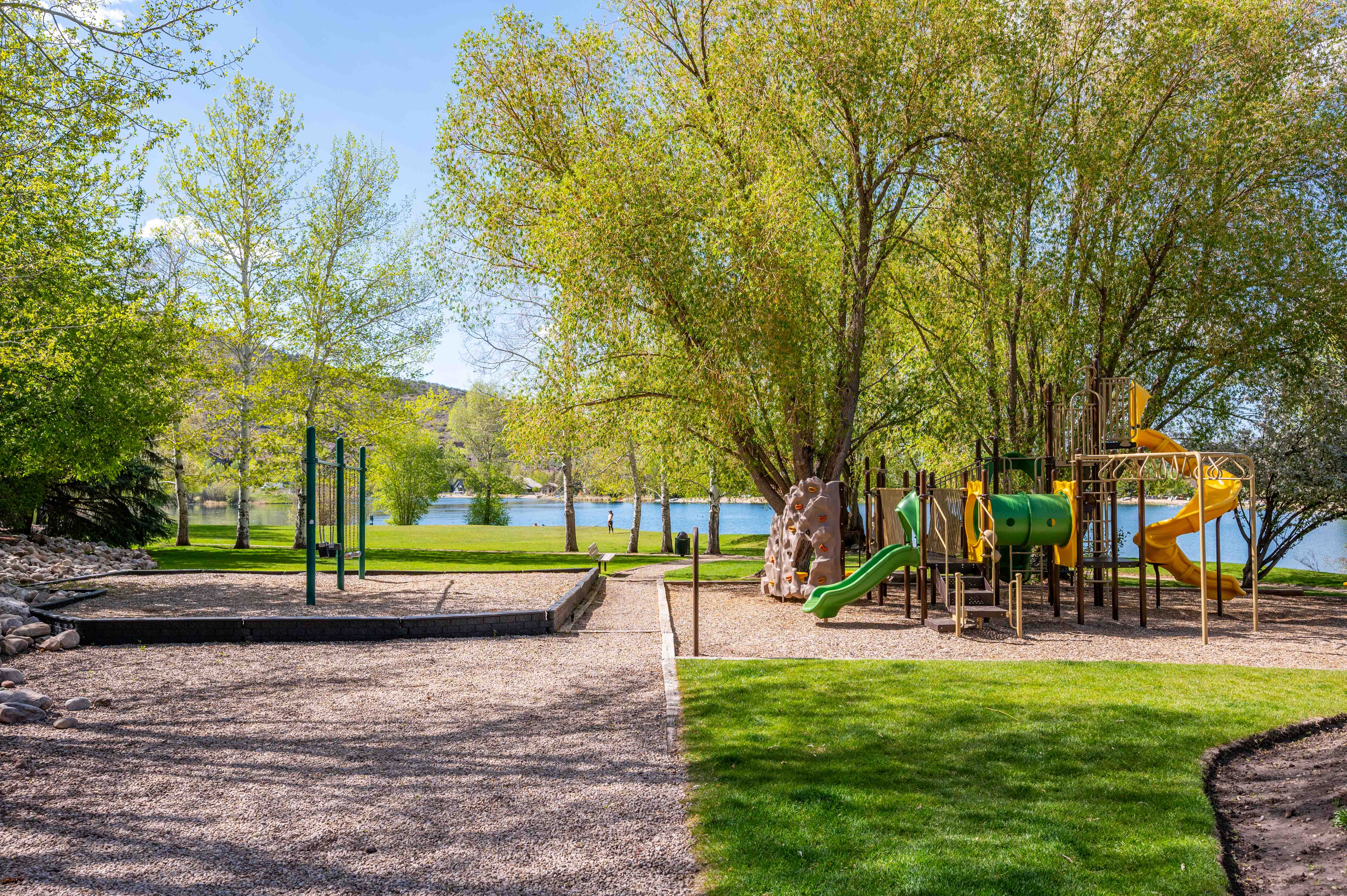 Expansive outdoor amenity area featuring a vibrant playground with multiple slides, a rock-climbing wall, and a monkey bar structure