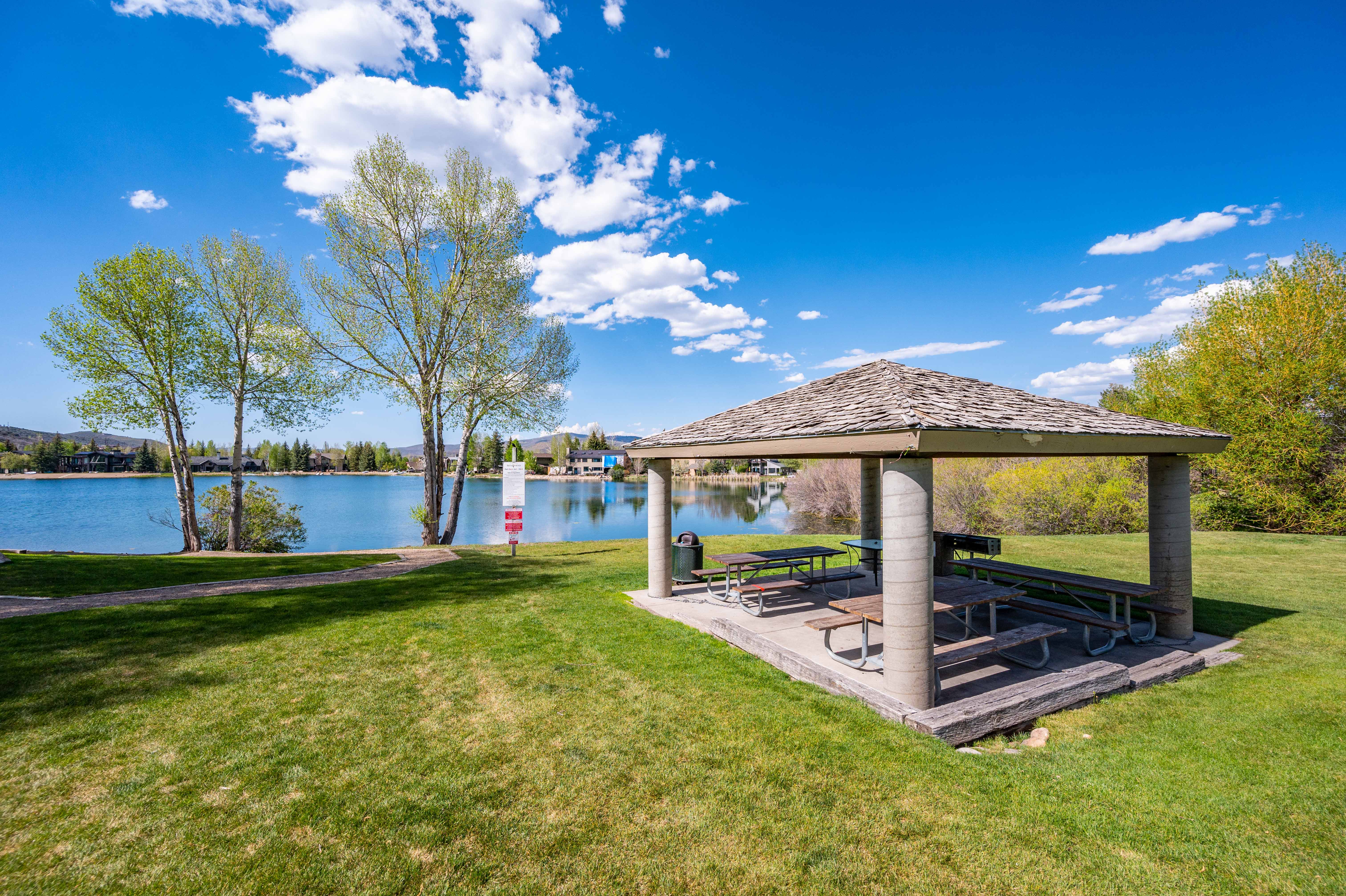 Lakeside pavilion featuring a shingle roof, concrete columns, and multiple picnic tables