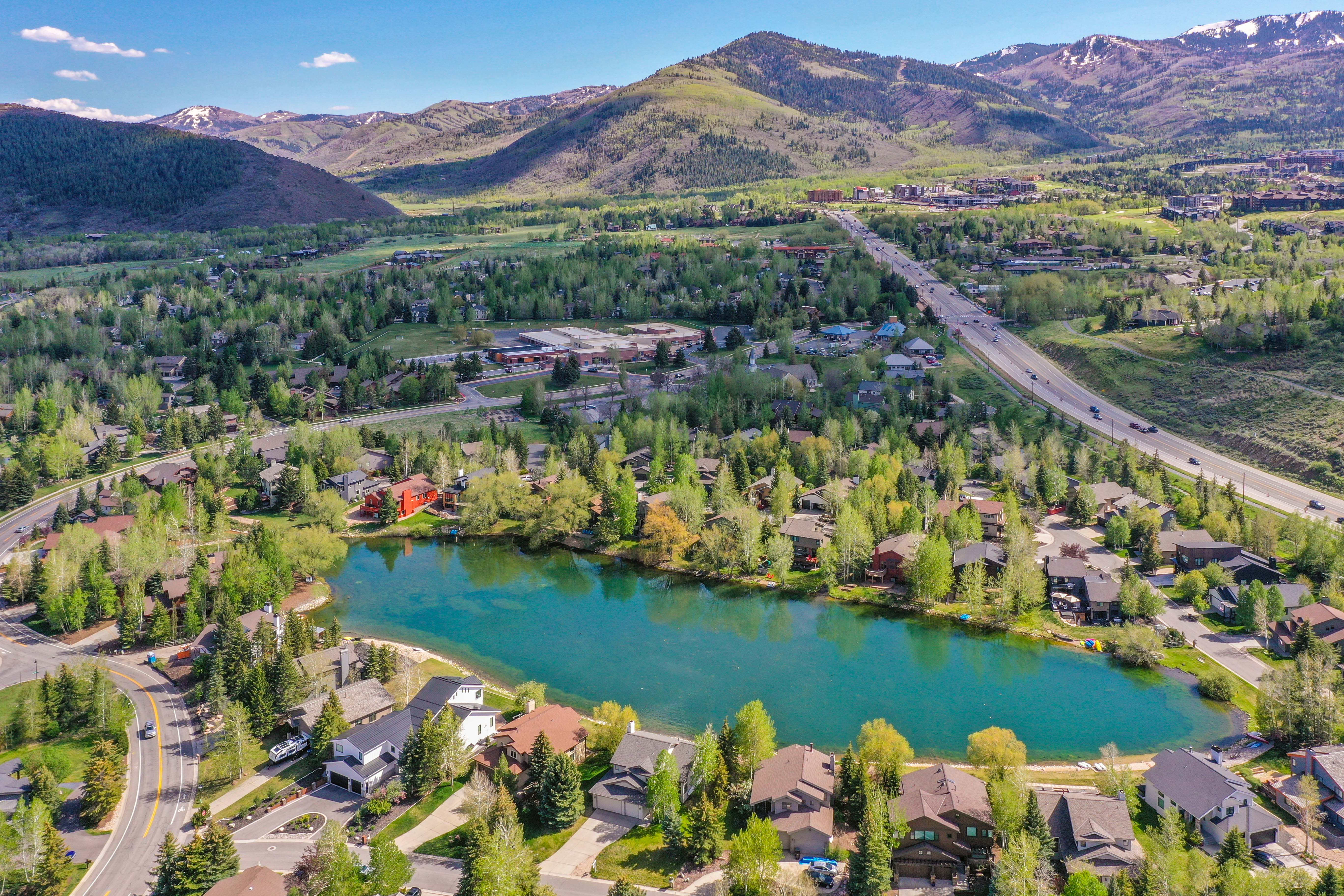Aerial perspective showcasing a residential area with a prominent central lake, surrounded by mature trees and varied architectural styles