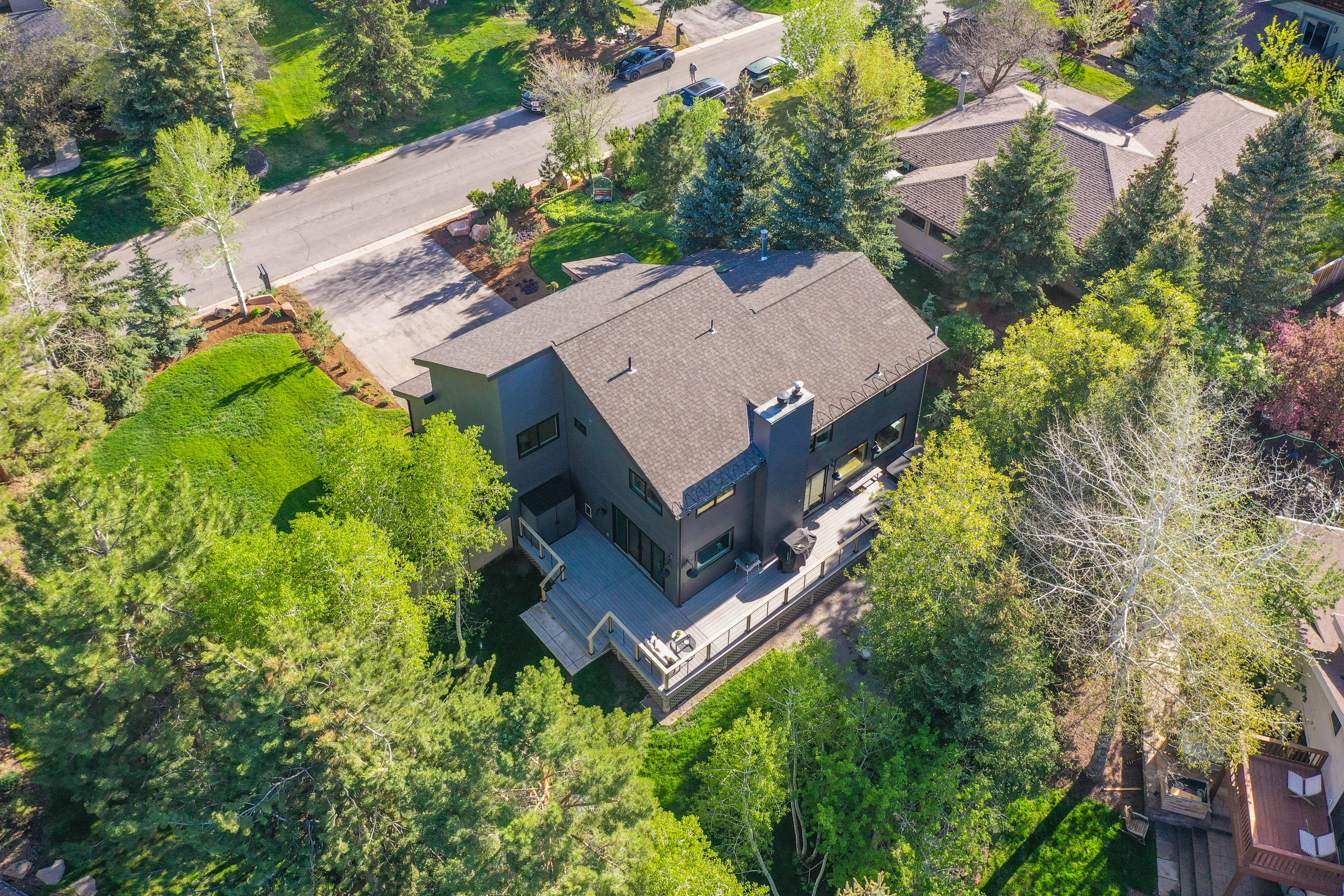 Contemporary multi-story residence featuring a dark exterior, a prominent rooftop, and a large multi-level deck with dark railings