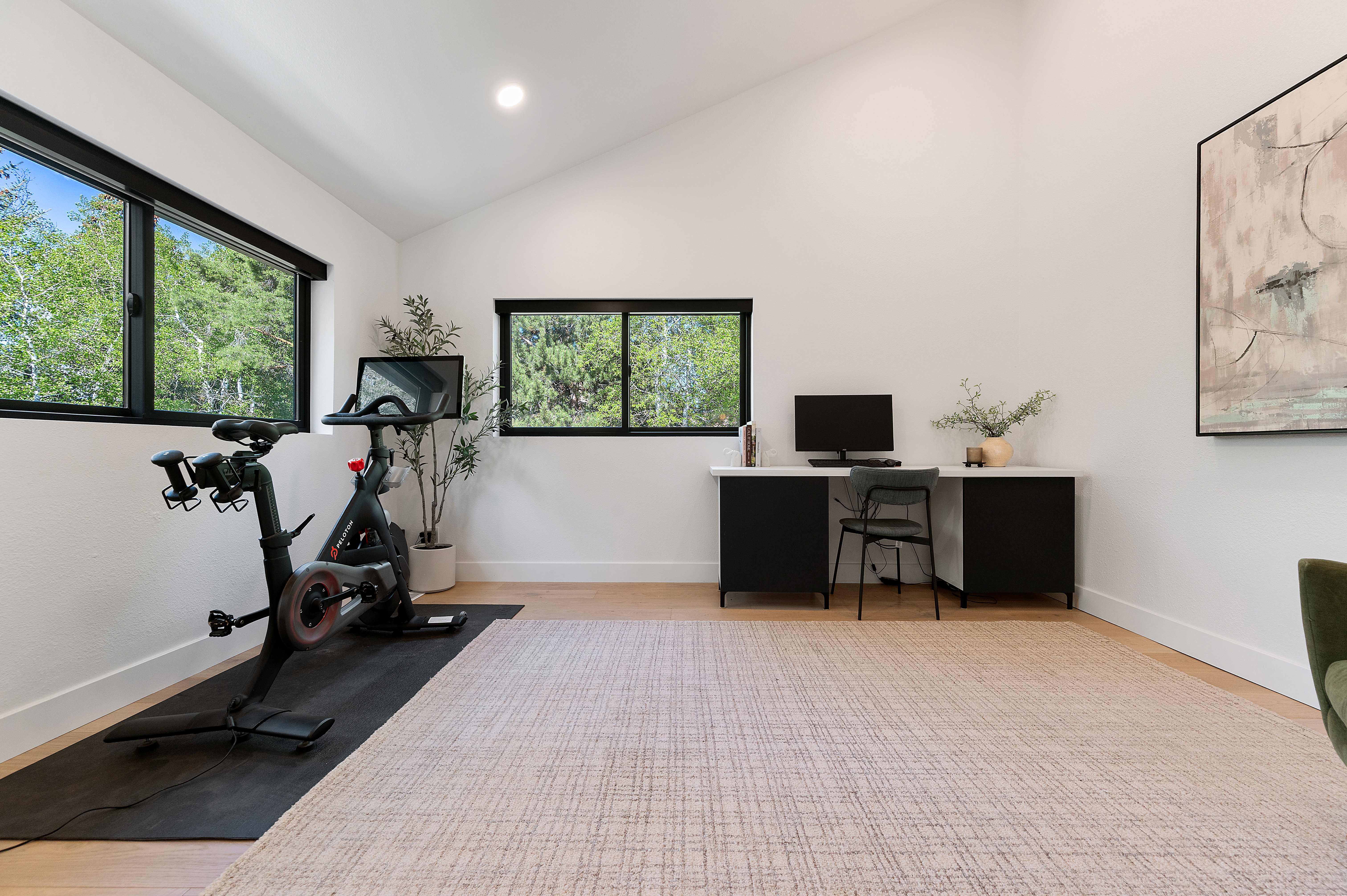 Vaulted ceilings with recessed lighting, light wood-finish flooring, and black-framed windows