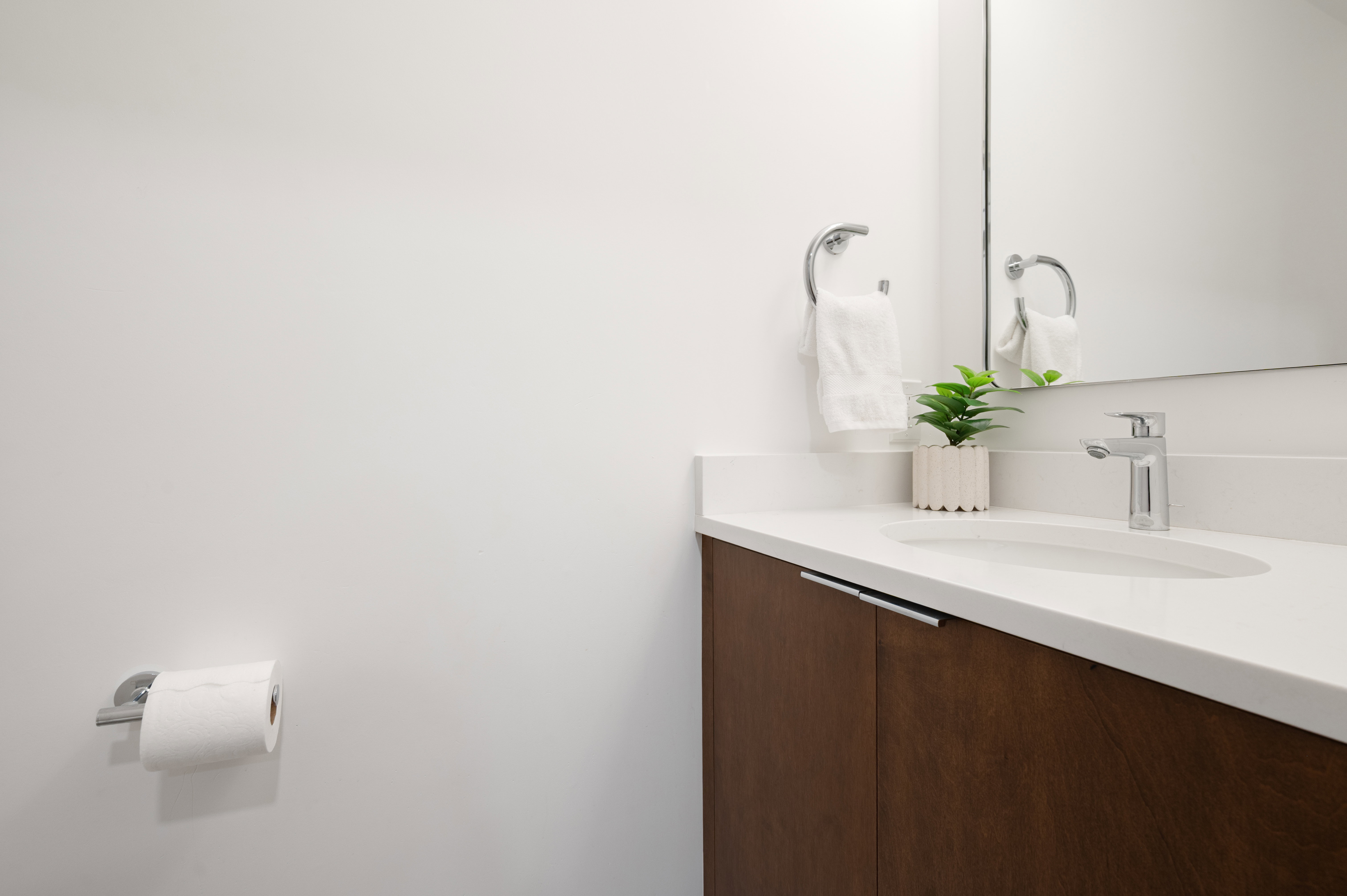 Contemporary vanity featuring a wood-finish cabinet, integrated sink, and white countertop