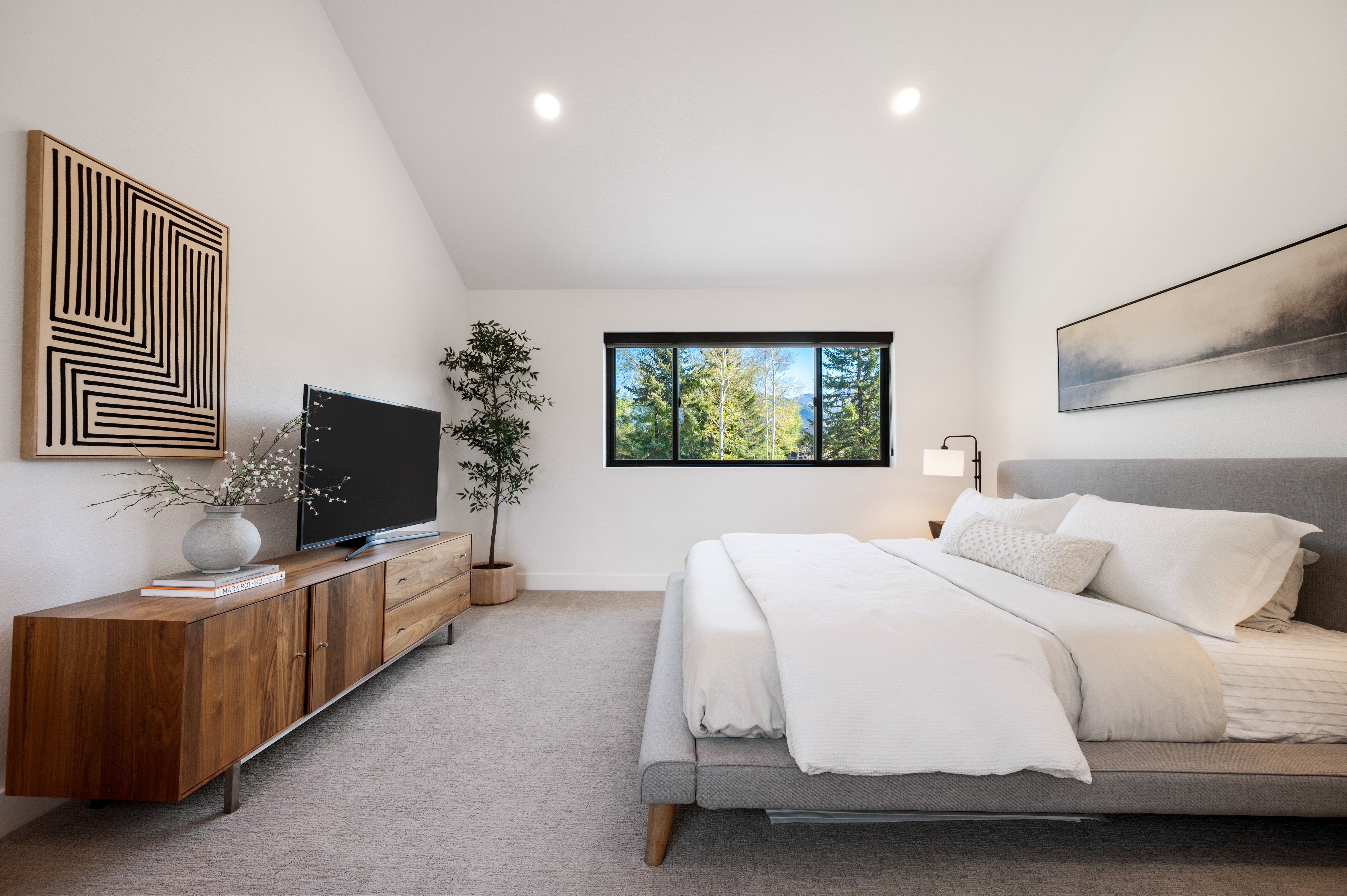 Vaulted ceilings above a carpeted room featuring a large window with a natural landscape