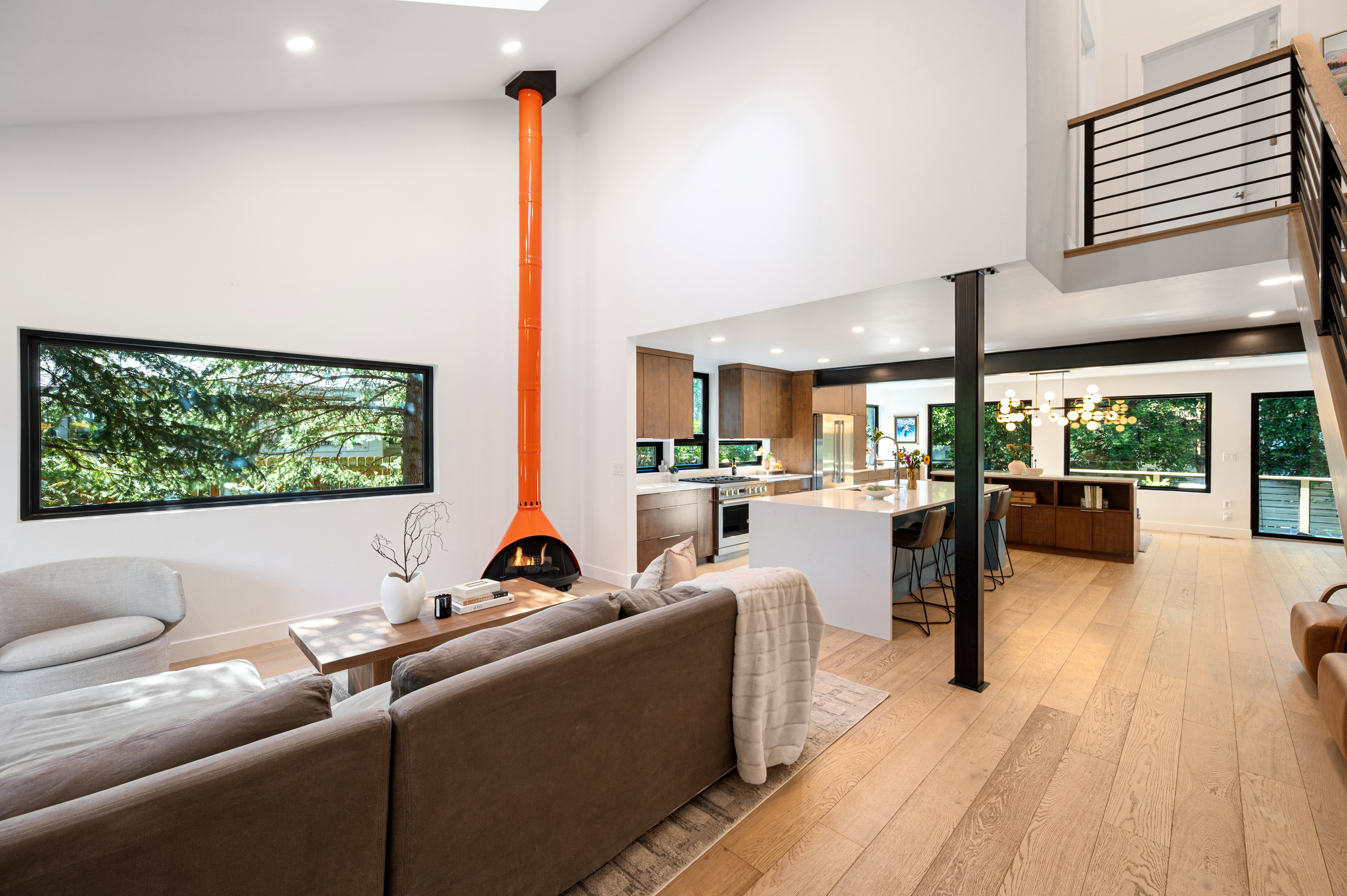 Vaulted ceilings enhance this open-concept living space, featuring a unique freestanding orange fireplace