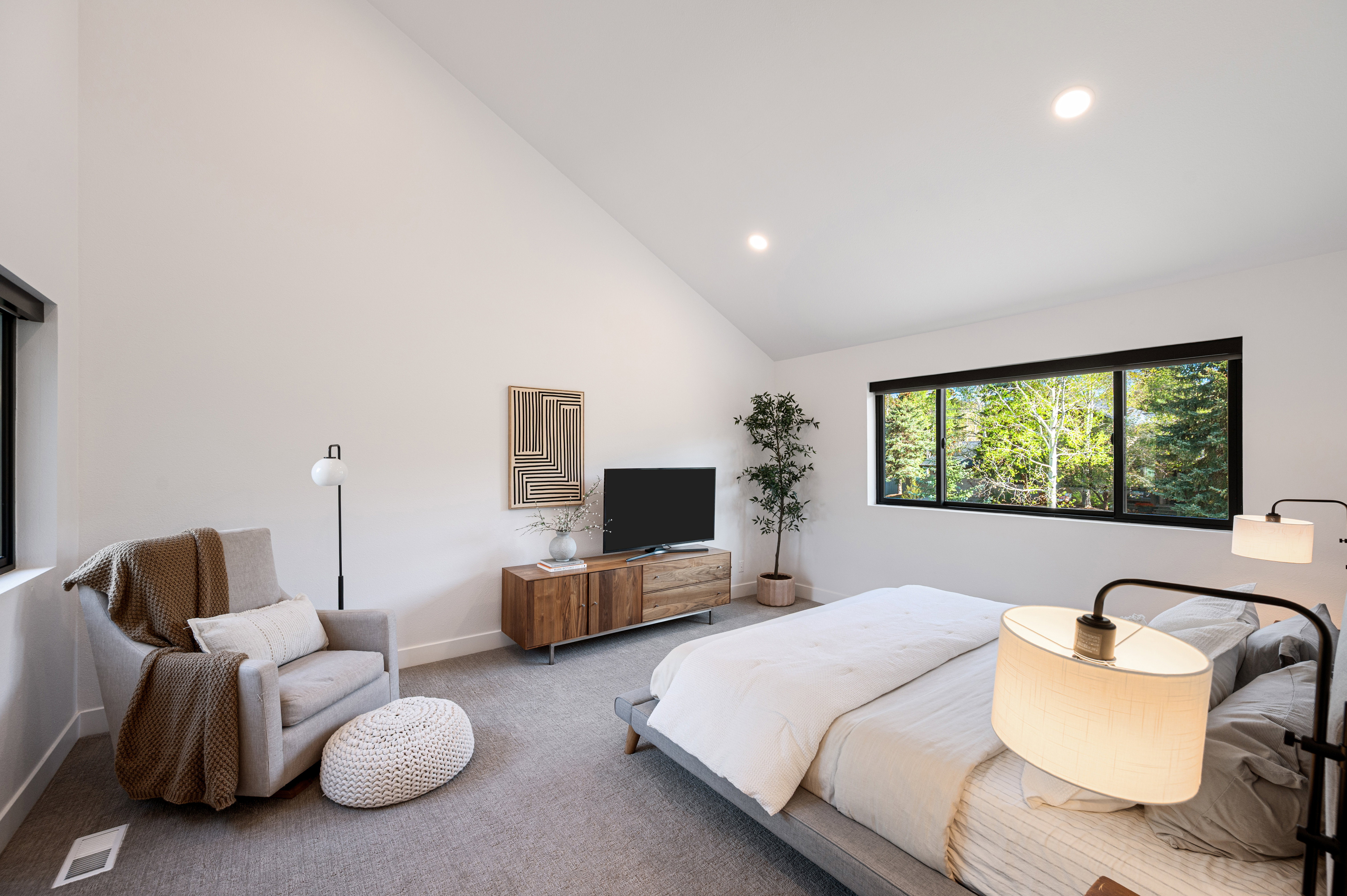 Vaulted ceiling bedroom with a large picture window, recessed lighting, and grey carpeting