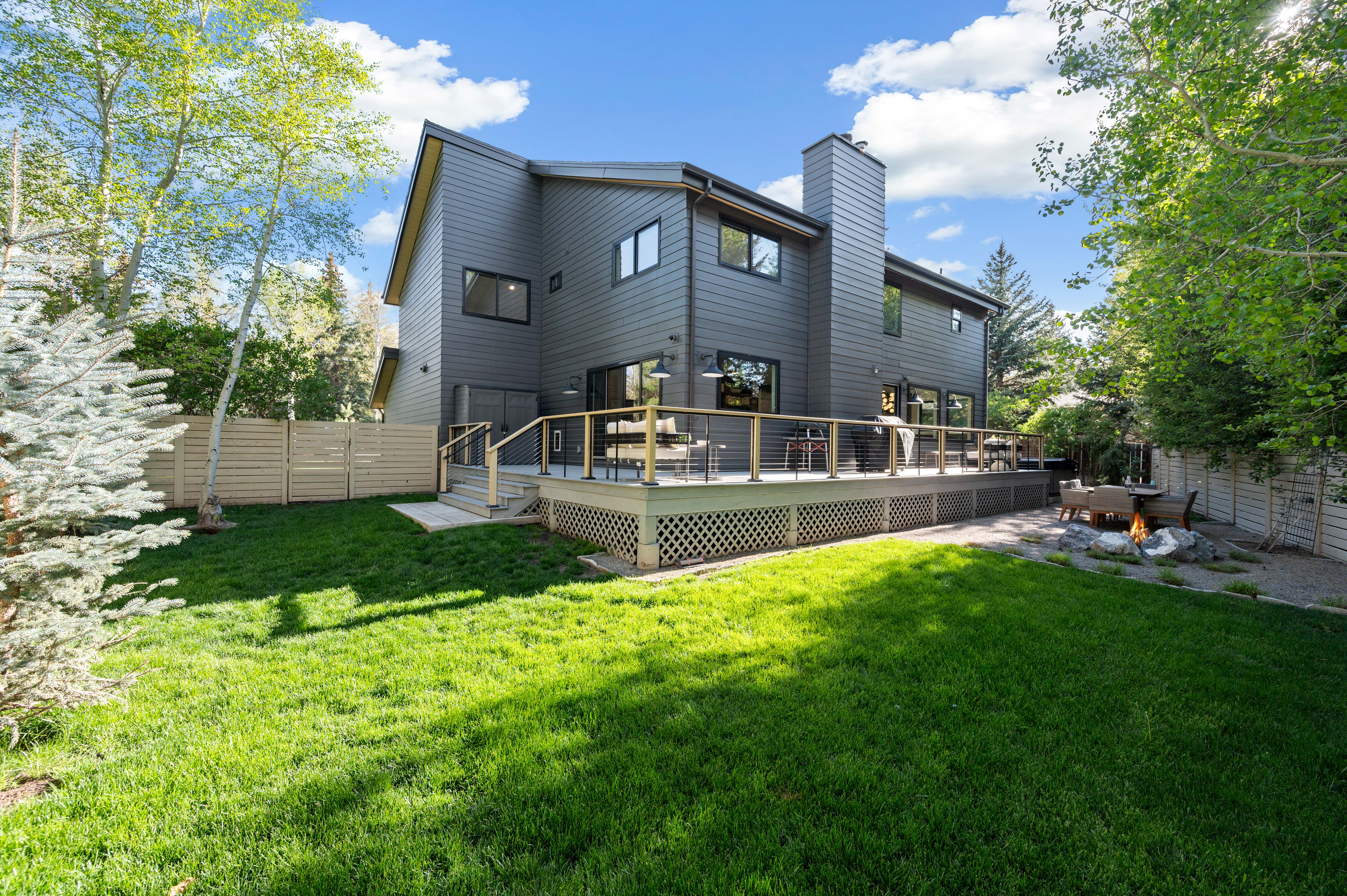 Modern gray siding exterior with a multi-level deck featuring wood railings and metal balusters