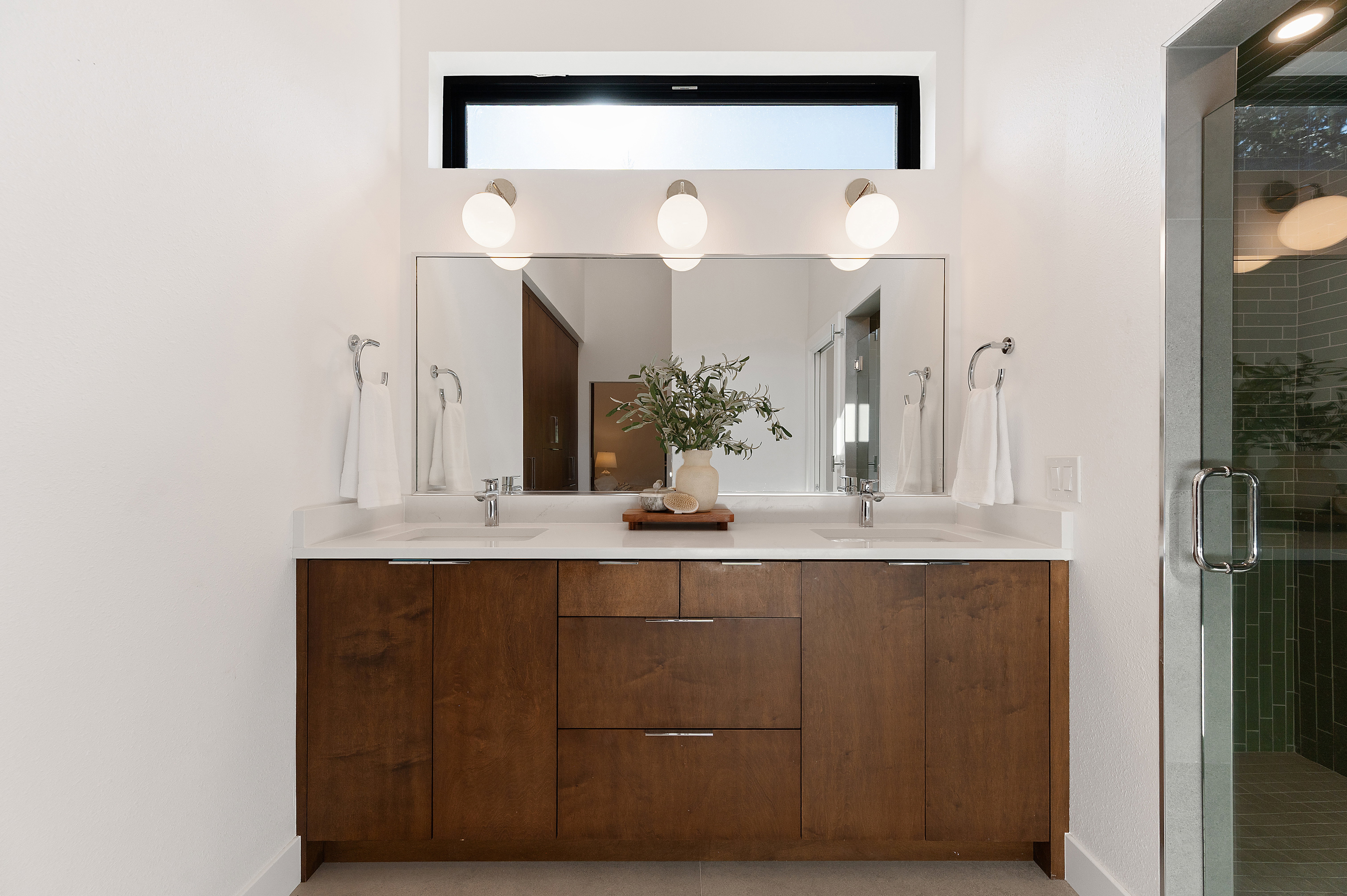 Double vanity with wood-finish cabinetry, white countertop, and dual undermount sinks